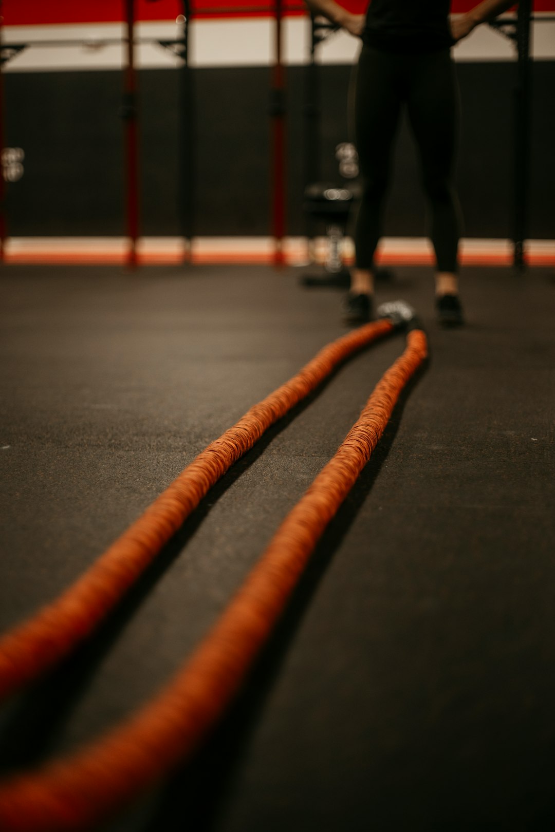 High-contrast image of heavy training ropes (battle ropes) on a gym floor, symbolizing metabolic conditioning.