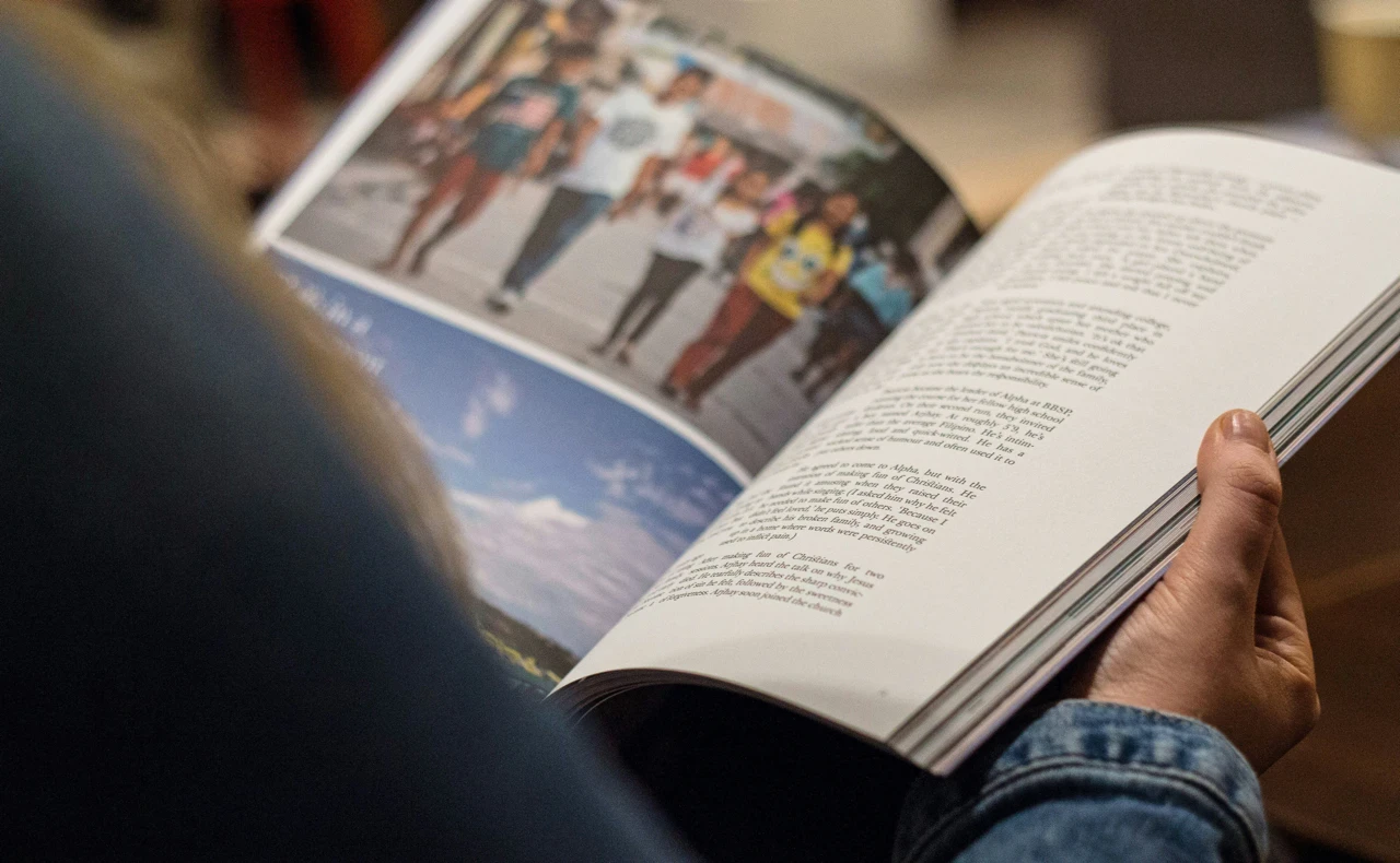 Person liest in Buch mit farbigen Bildern und Texten, Nahaufnahme.