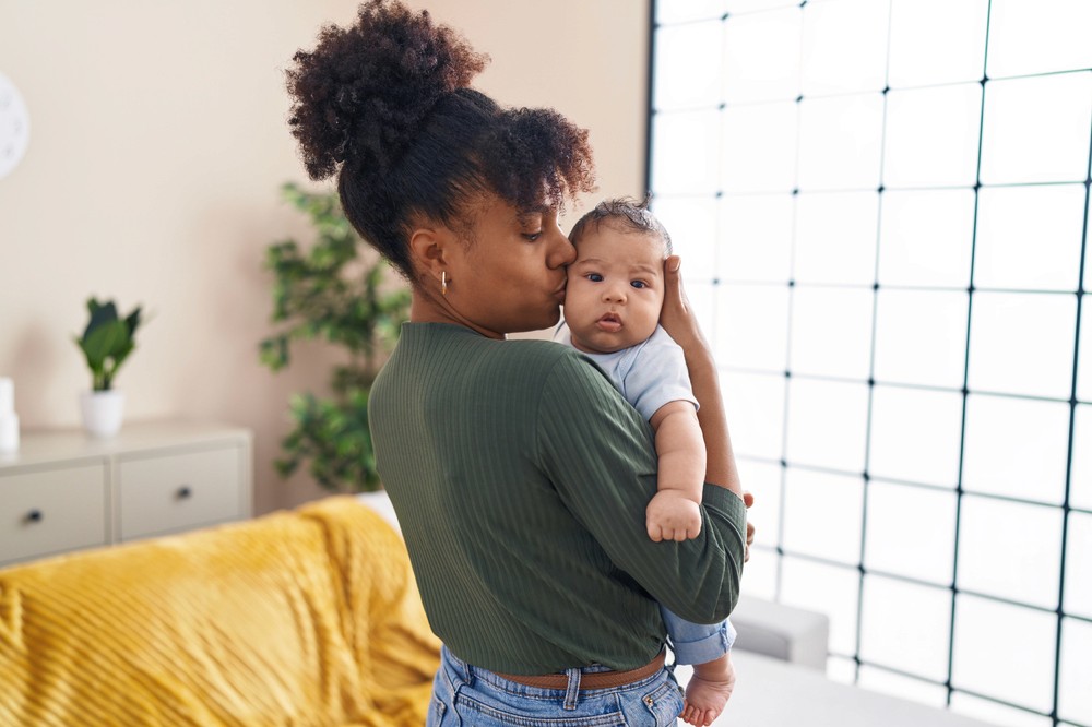 Mère tenant son bébé dans un moment de tendresse, illustrant l'importance de protéger ses proches avec une assurance vie.