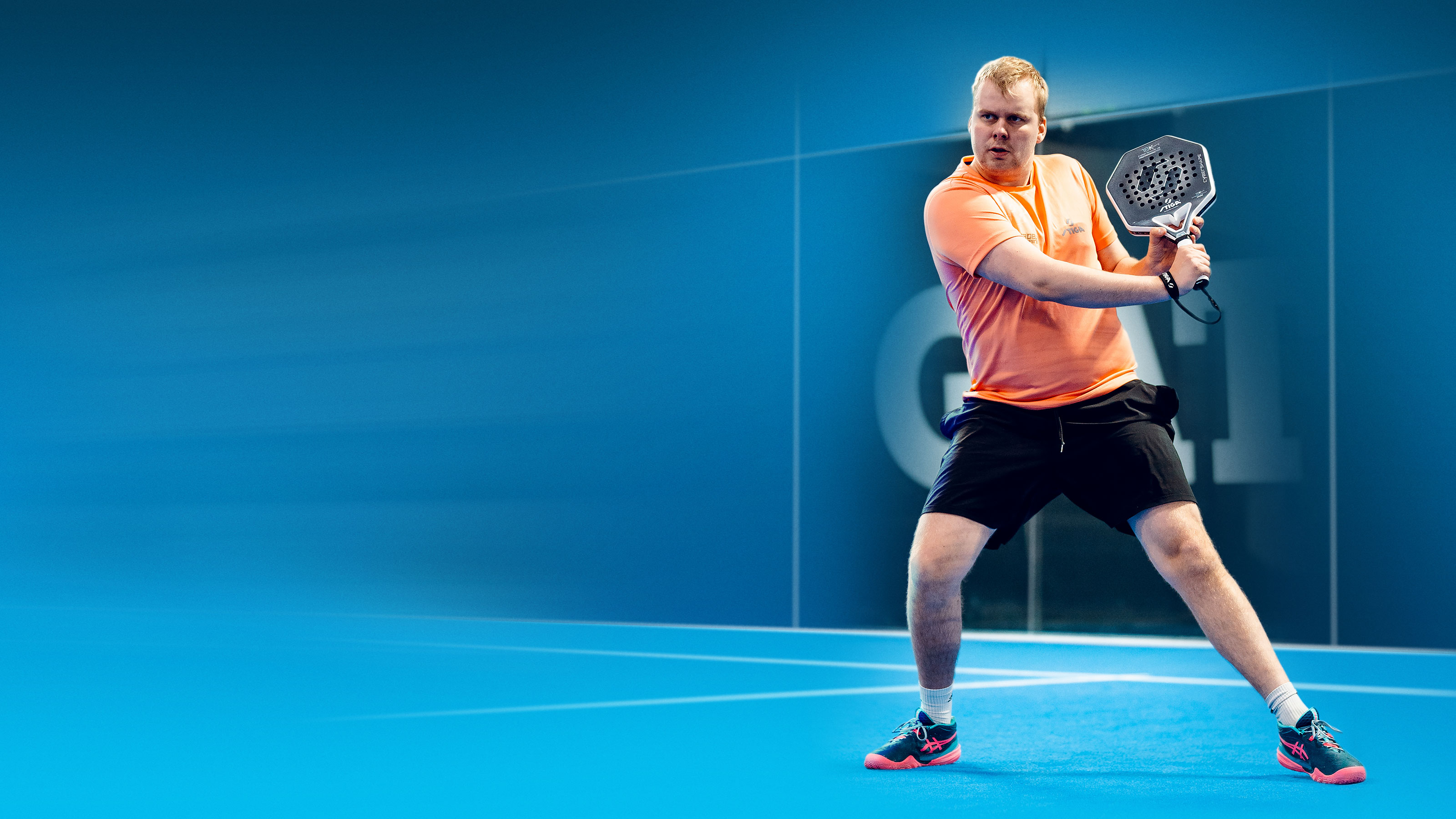 Antti Kampman padel-kentällä lyömässä volleyta