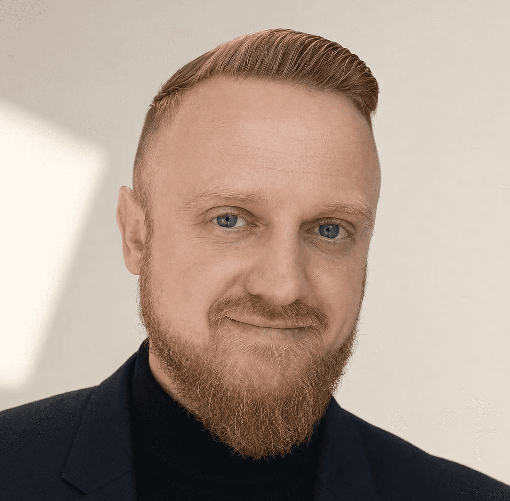 Profile portrait of a man in a blazer against a light background