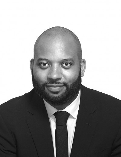 A black and white photo of a man wearing a suit and tie.