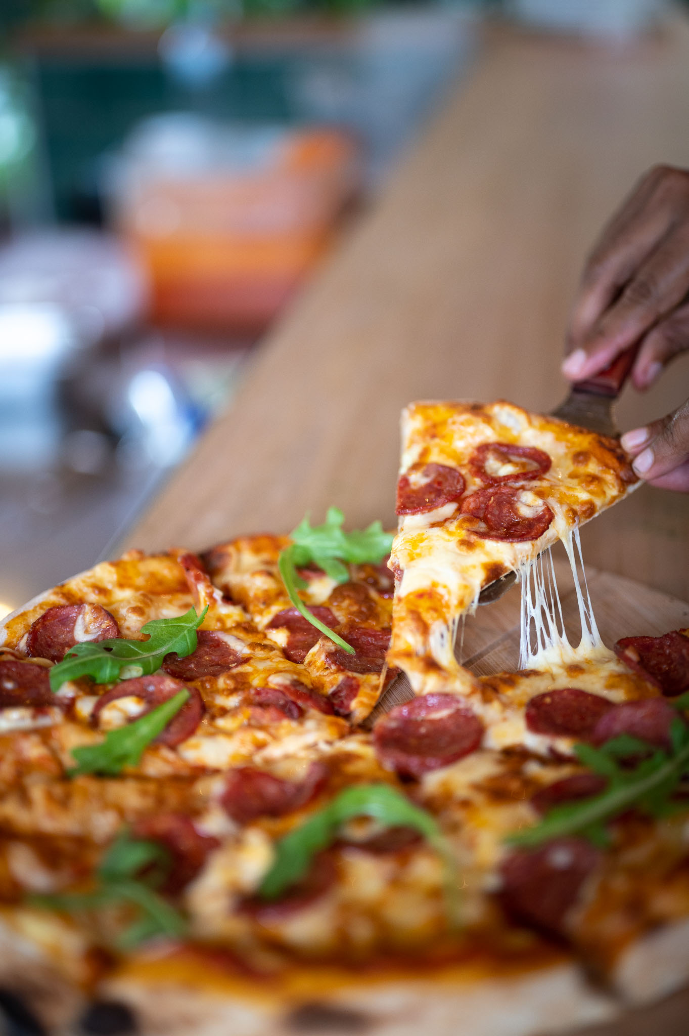 Stretchy cheese being pulled from a slice of pepperoni pizza fresh from the oven.