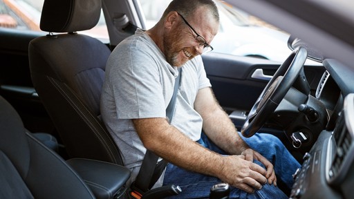 man holding knee in pain while in car