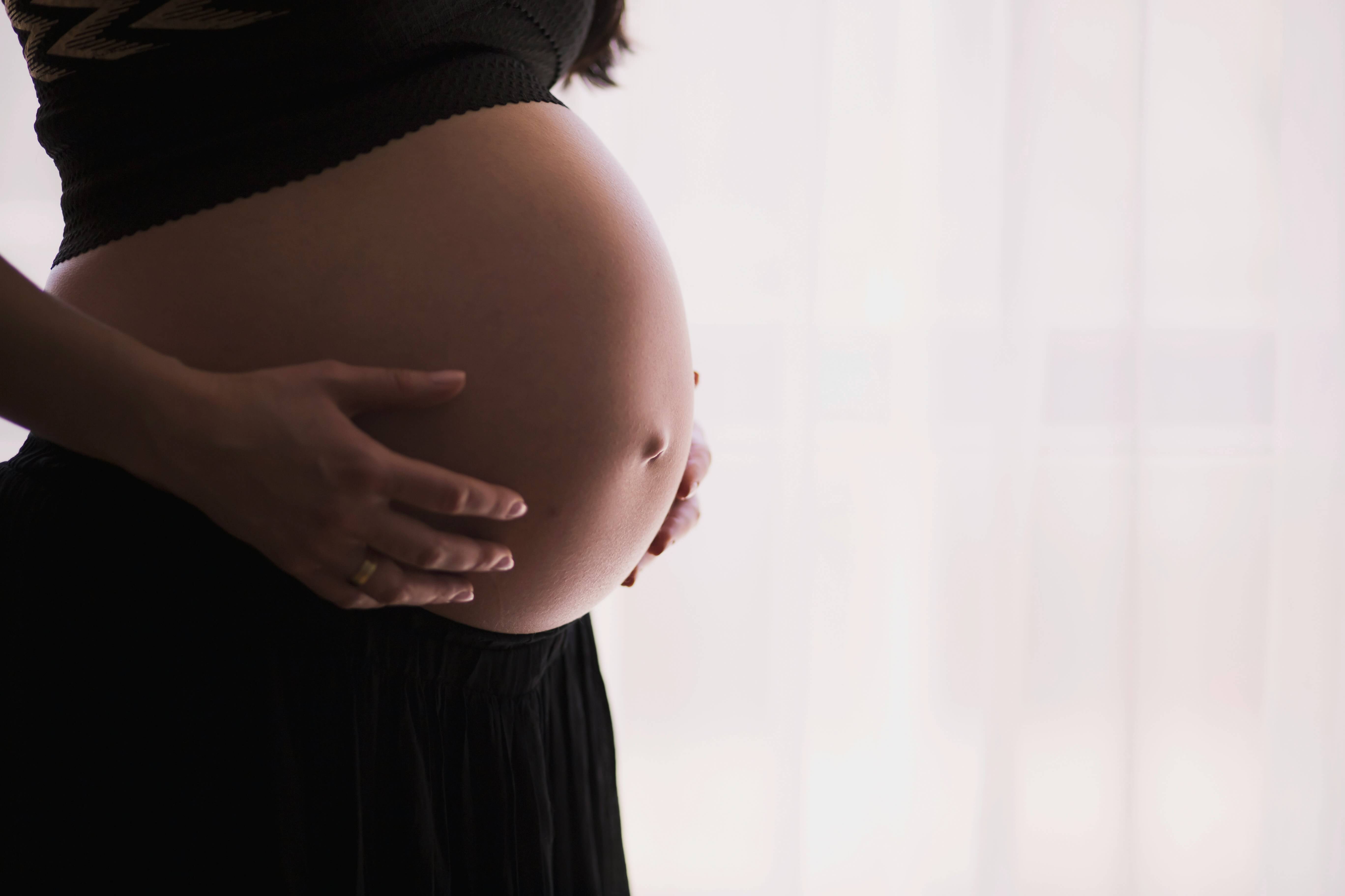 A pregnant woman holding her stomach.