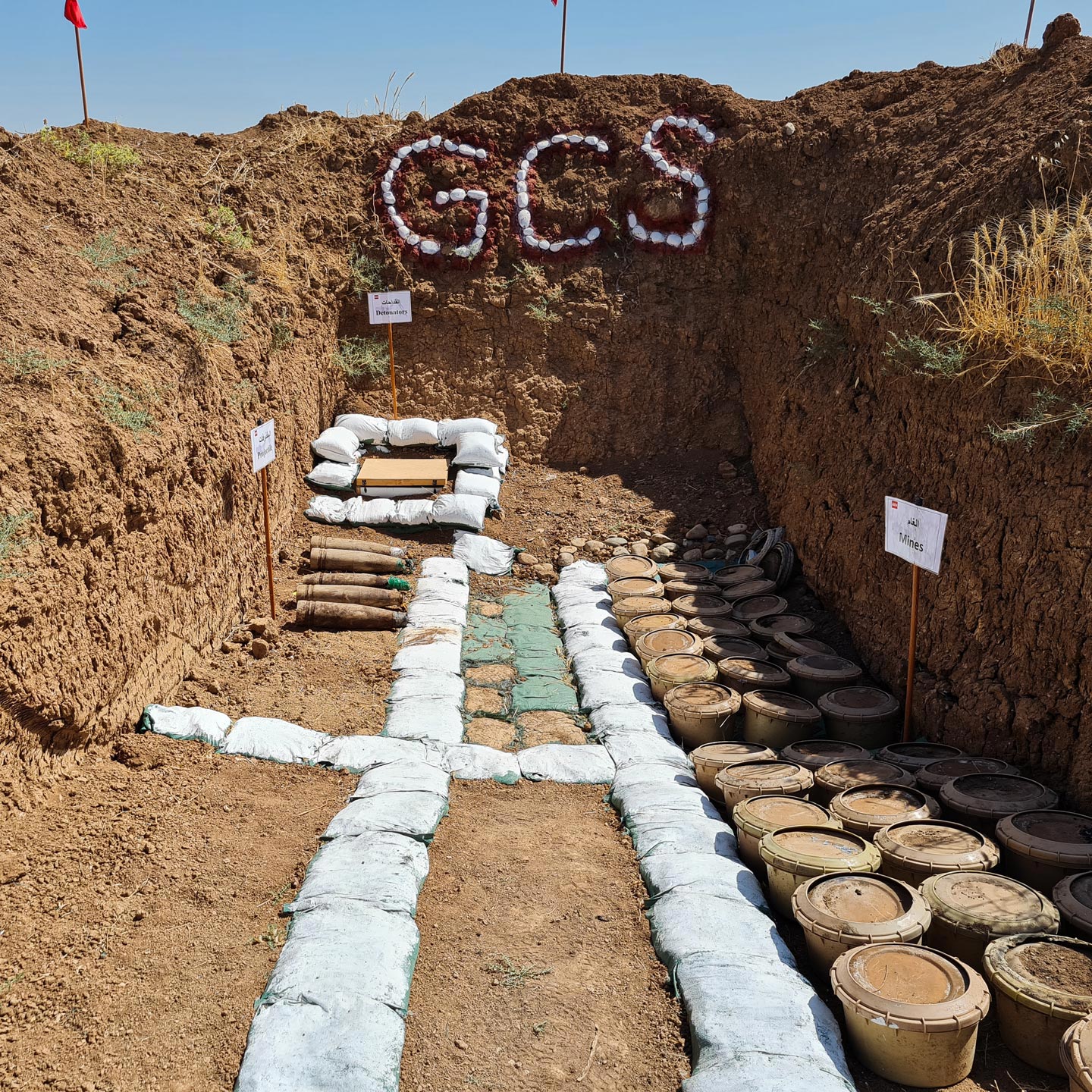 GCS demolition pit containing recovered landmines, artillery shells and detonators prepared for controlled destruction during EOD operations in Iraq.