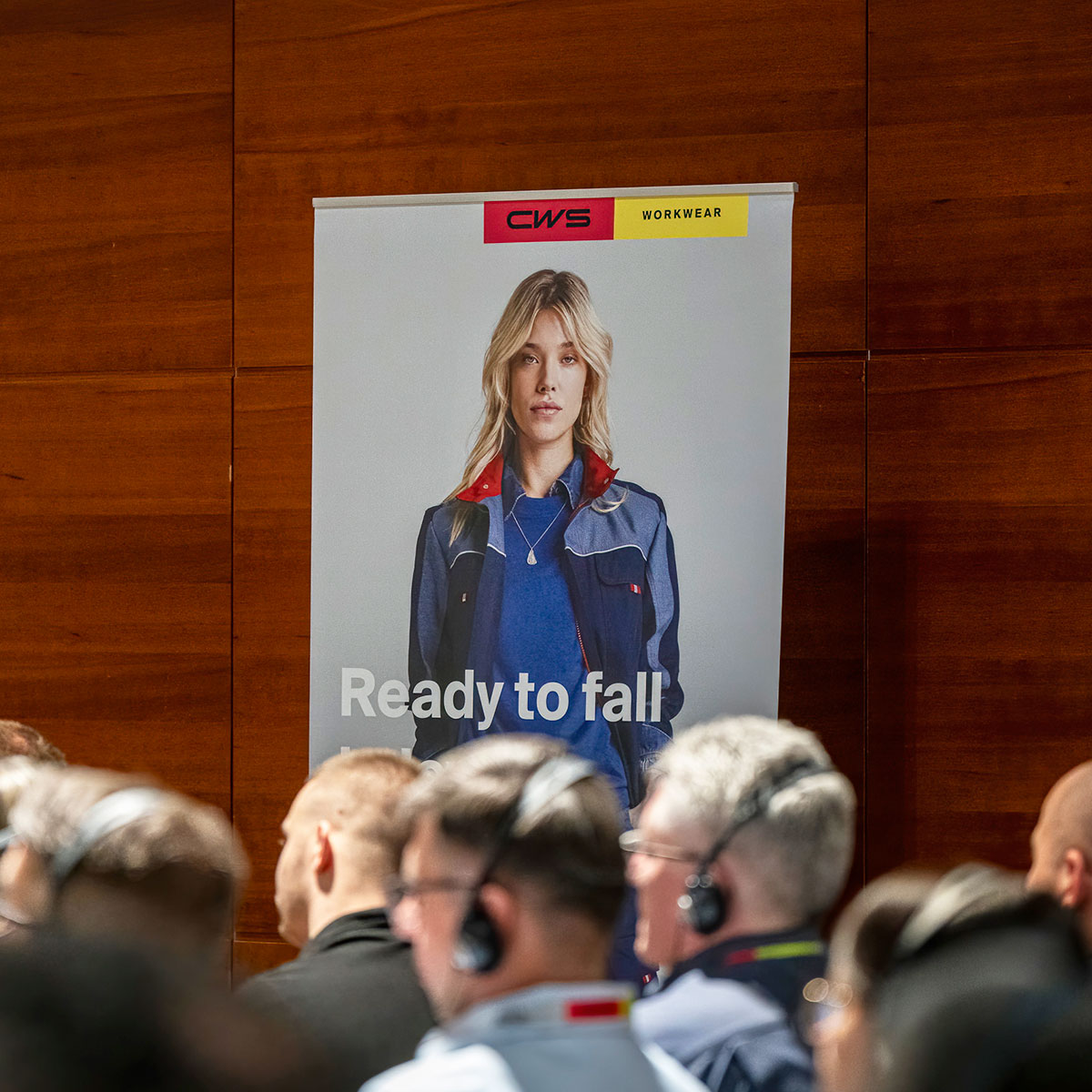 Event branding displayed behind attendees during a corporate conference session.