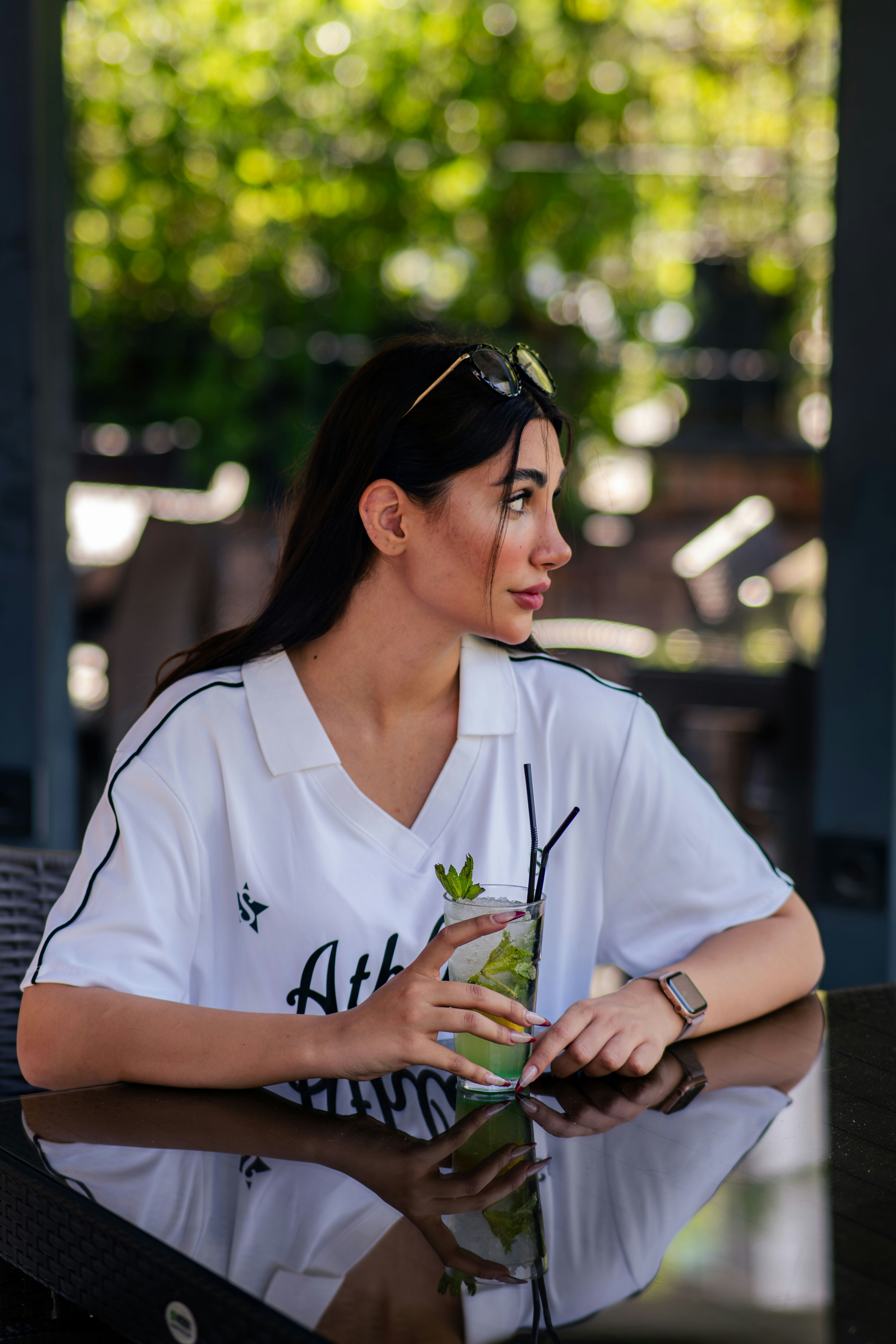 Woman holding a refreshing drink at an outdoor cafe.