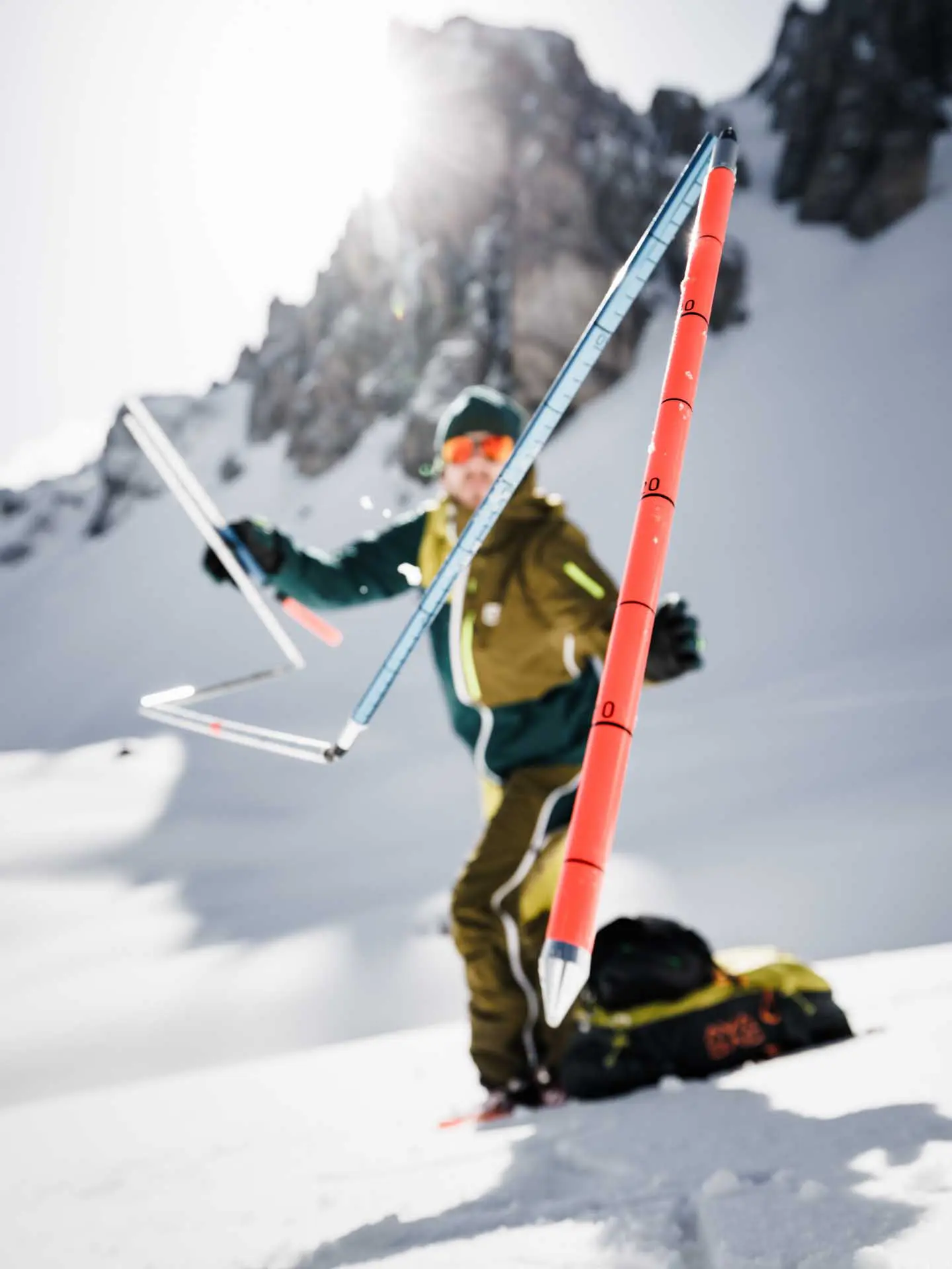 Avalanche rescue training in alpine terrain, with a participant practicing probing techniques in deep snow