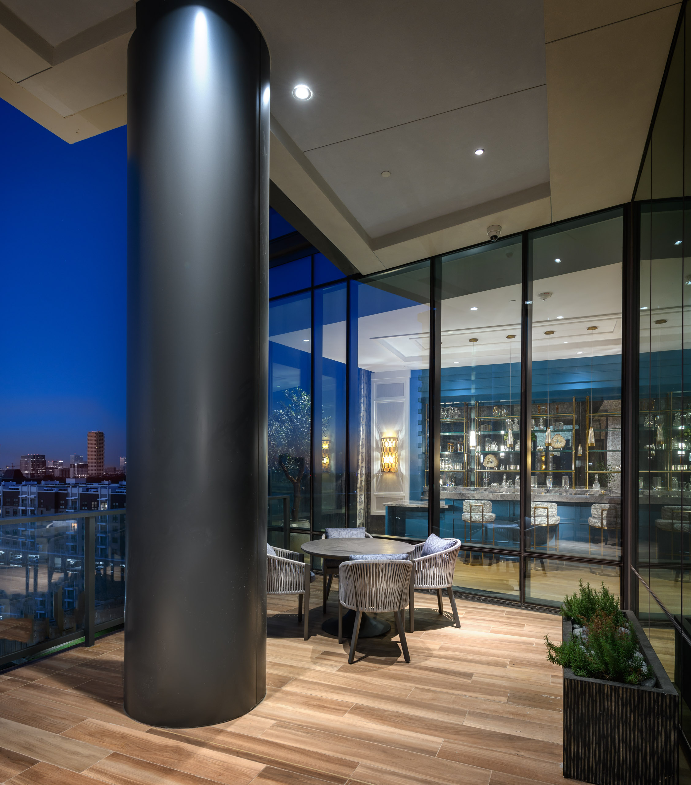 Outdoor seating on a balcony at dusk with city view.