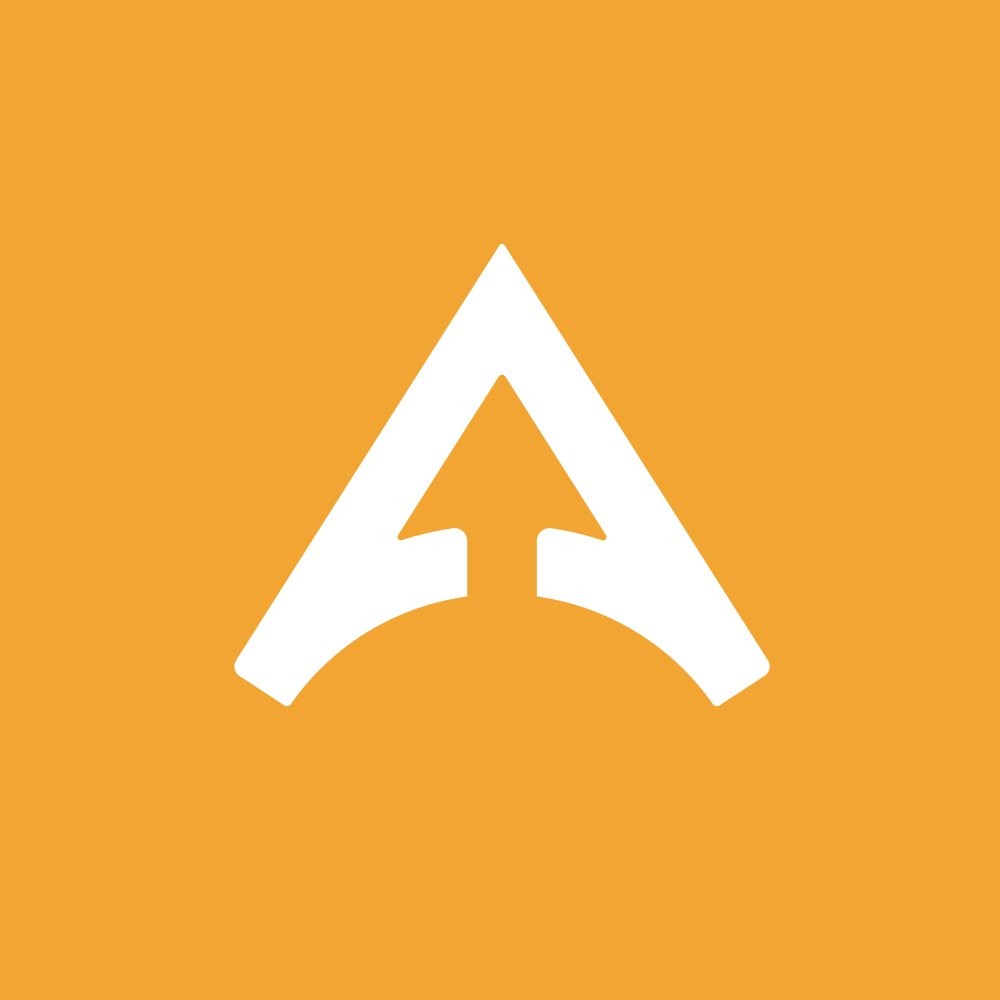 A young man with light brown hair is wearing a black suit jacket and white shirt, standing in a softly lit office setting, conveying professionalism.