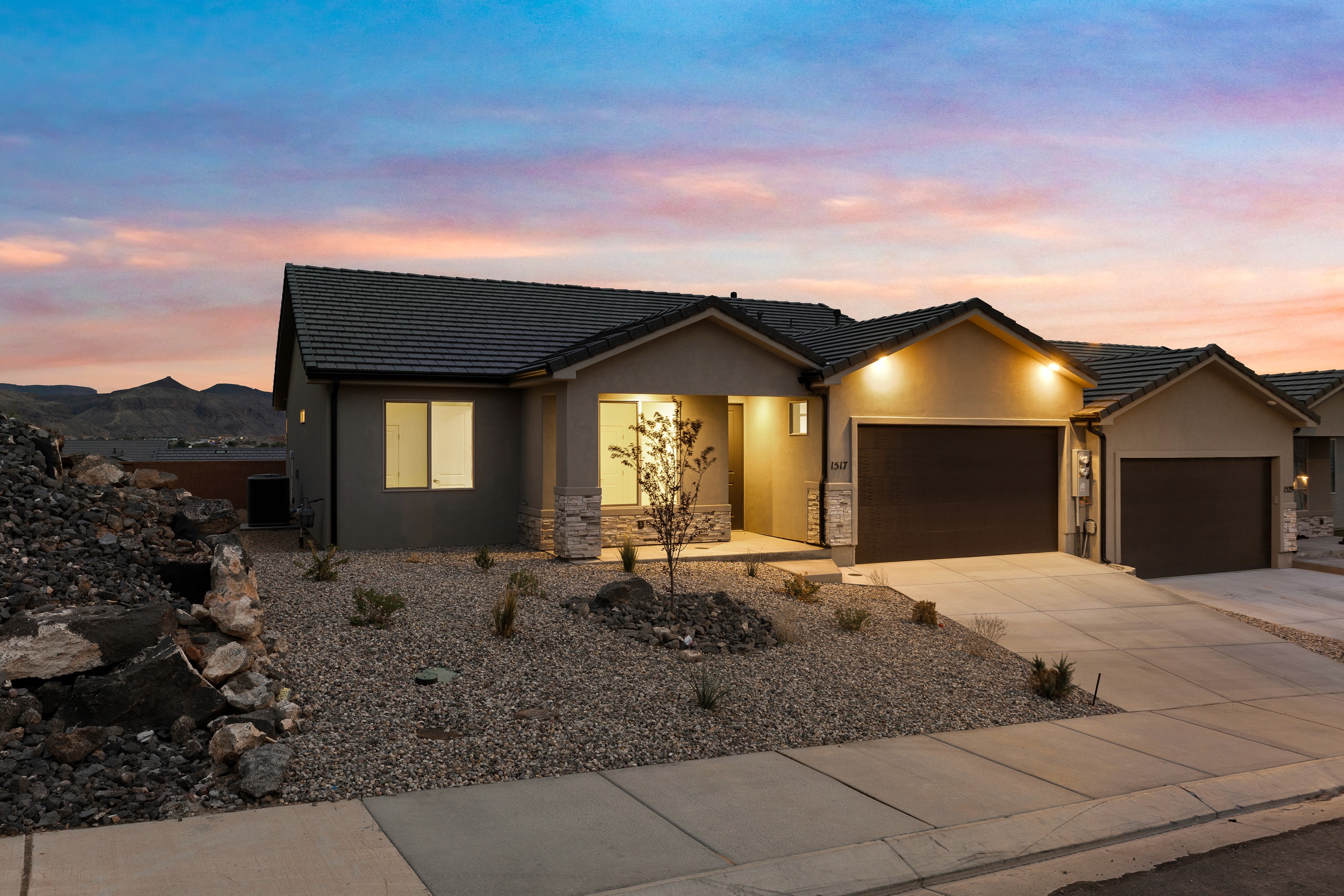 Evening view of The High Desert Home in Hurricane Utah with illuminated entryway and warm exterior lighting.