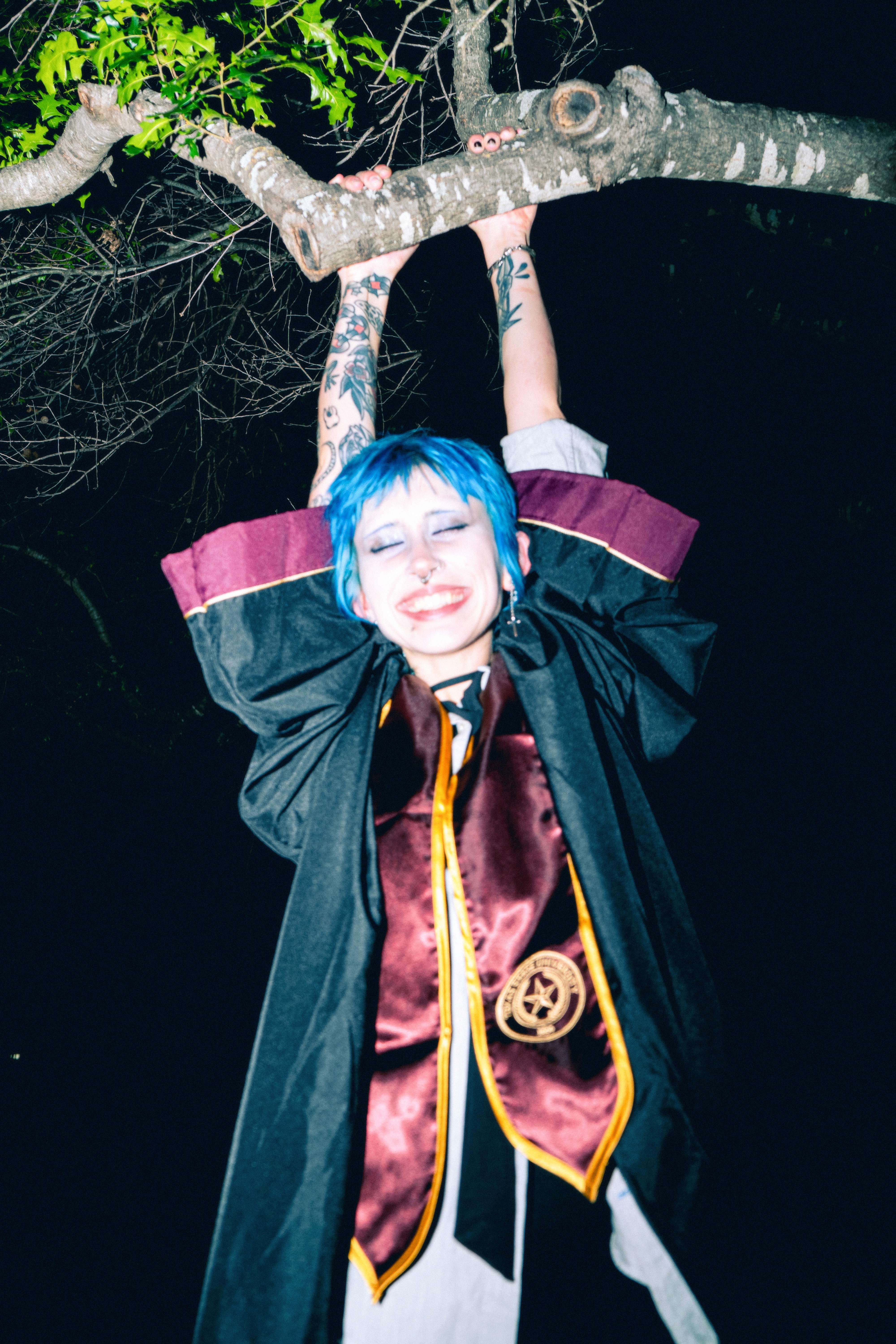Maggie holding onto a tree brand in graduation gown and stole