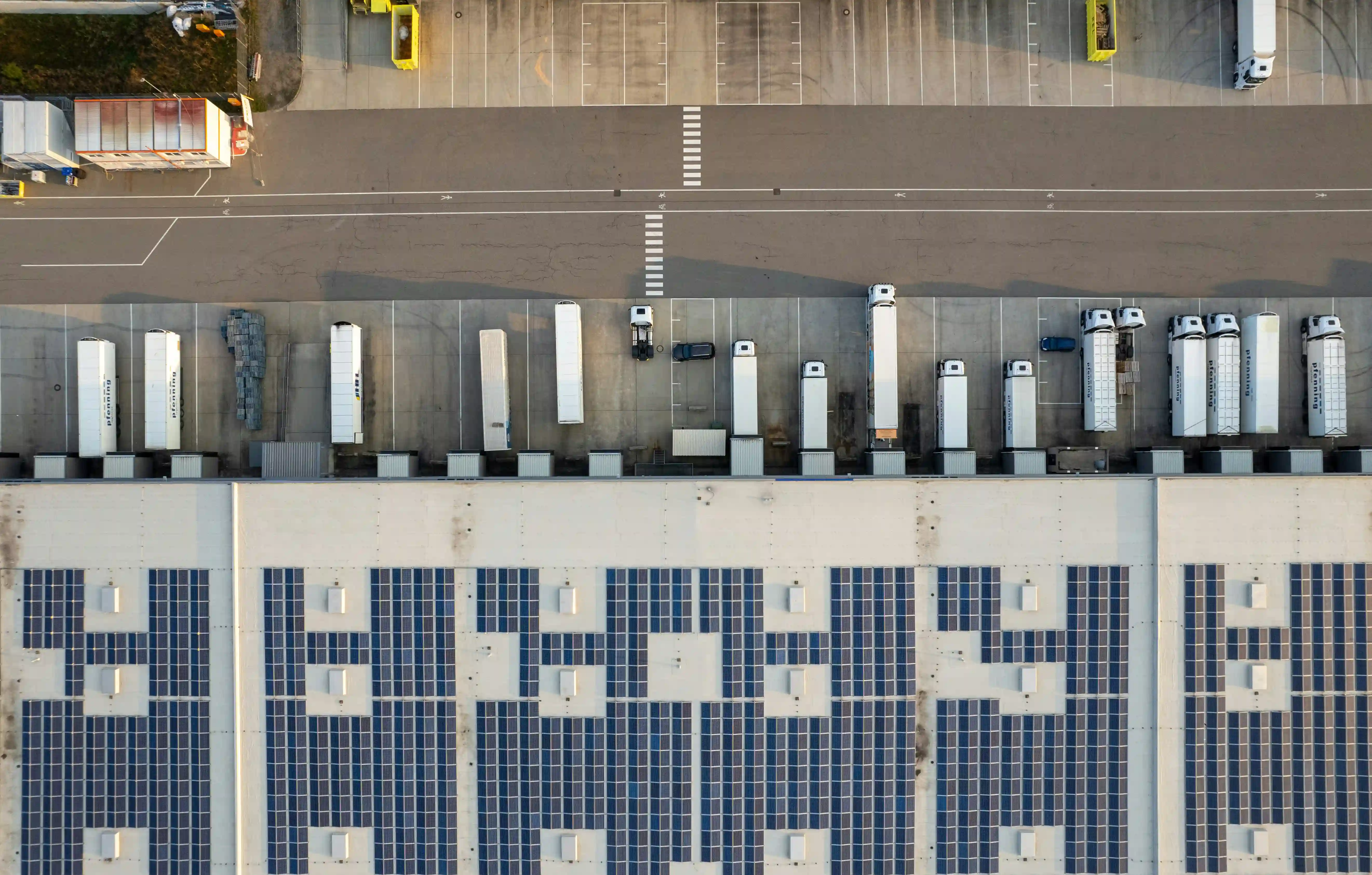 aerial shot looking down at freight trucks parked outside a fulfilment warehouse