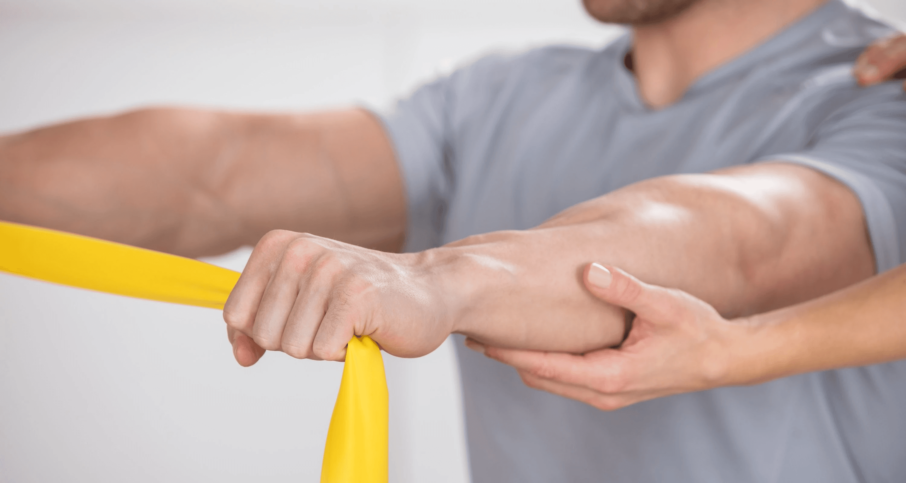 Patient der unter Anleitung ein Theraband auseinander zieht