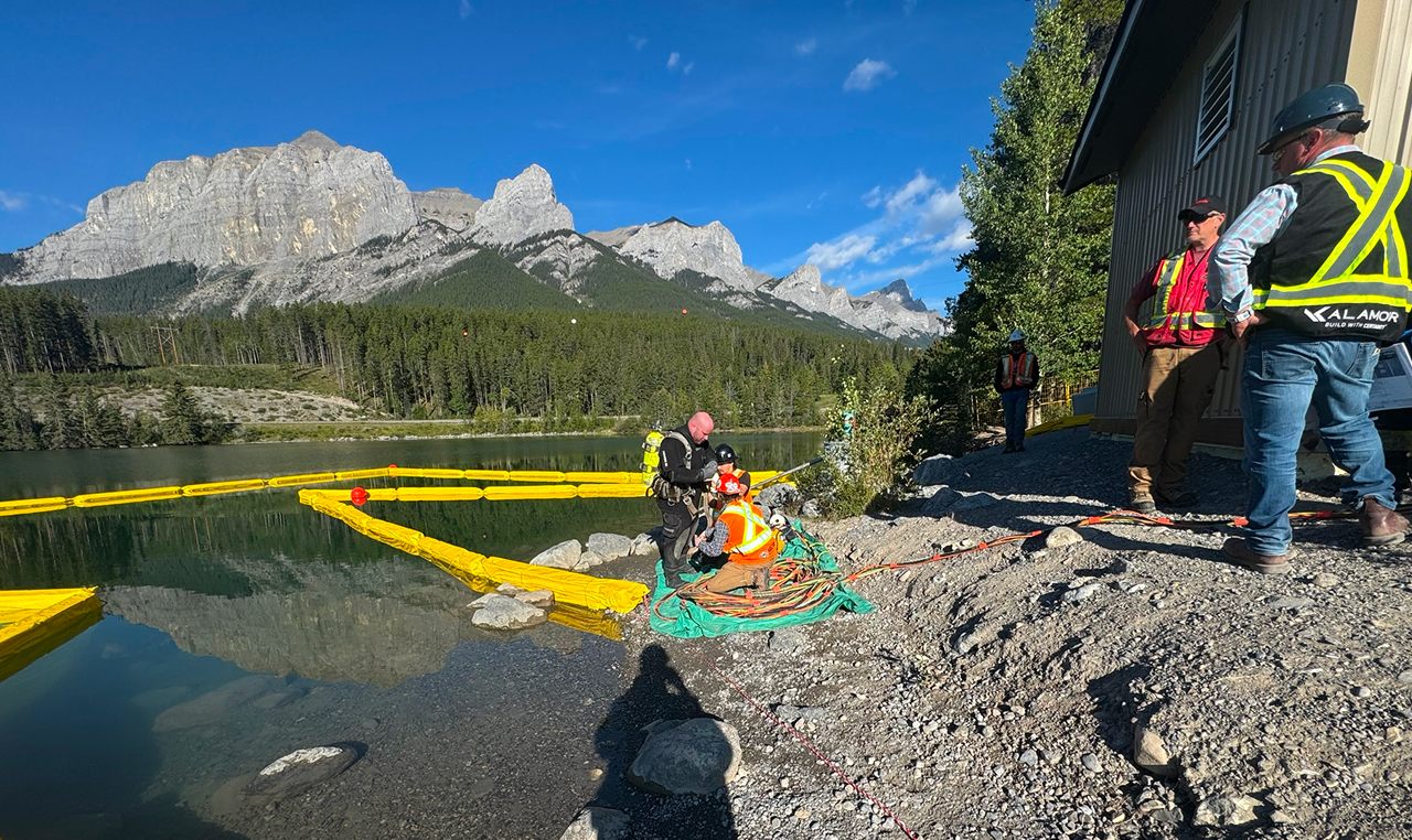 Diver conducting underwater inspection of water intake system with turbidity curtain at Canmore Nordic Centre