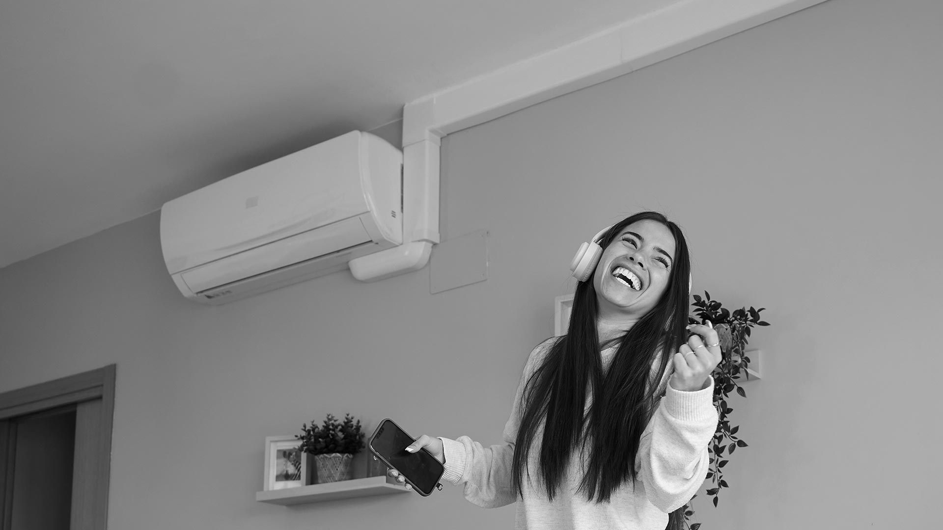 Сучасна спліт-система кондиціювання в кімнаті з озелененням та молодою жінкою