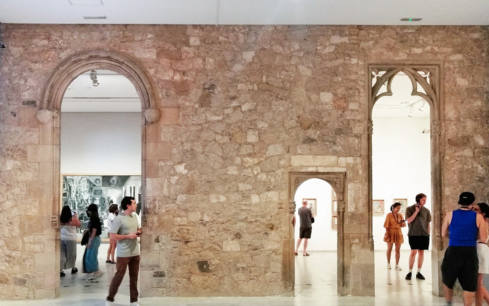 Visitors exploring exhibits at Picasso Museum Barcelona through stone archways.