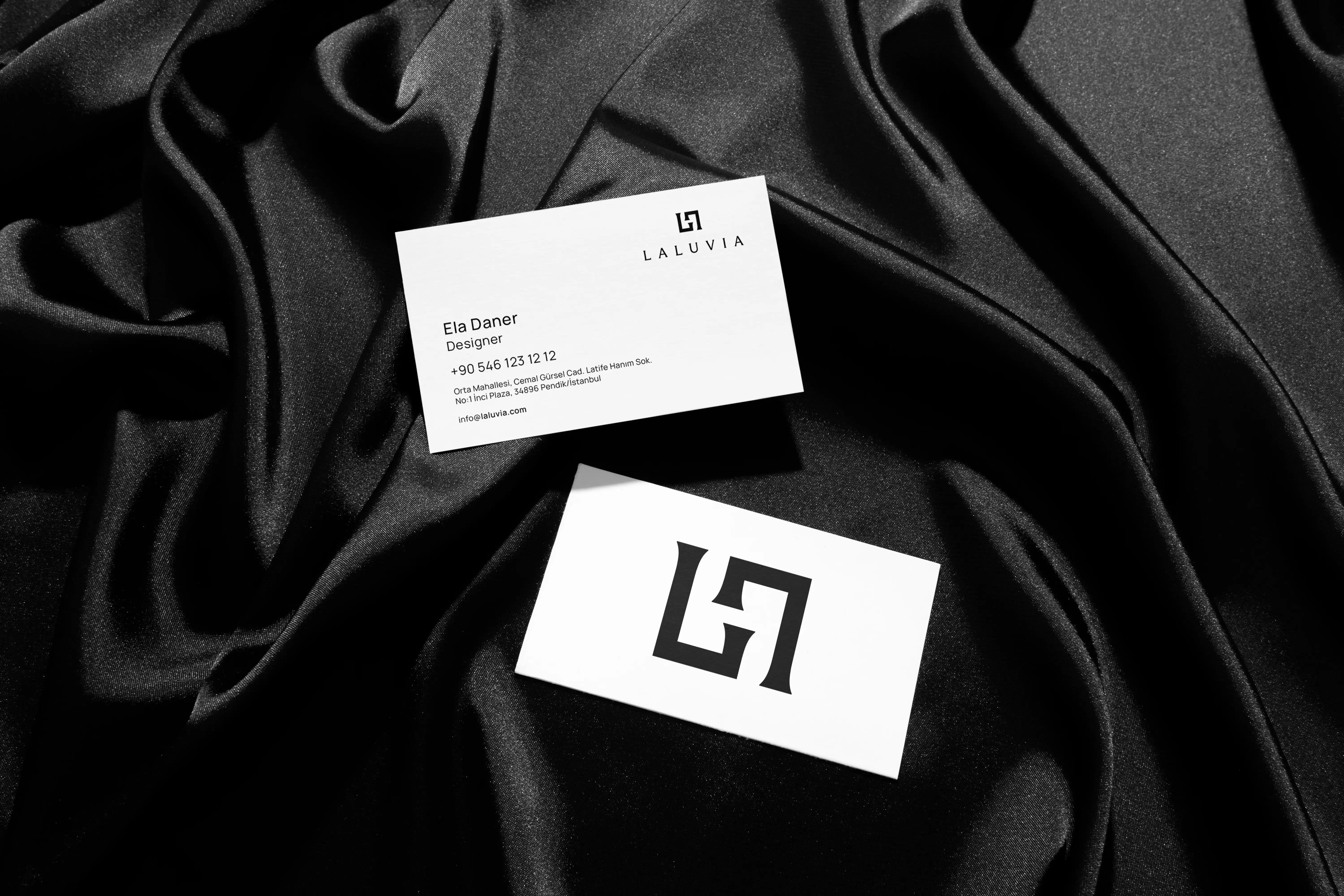 Professional Laluvia corporate business cards displayed on textured black silk fabric for a high-fashion aesthetic.