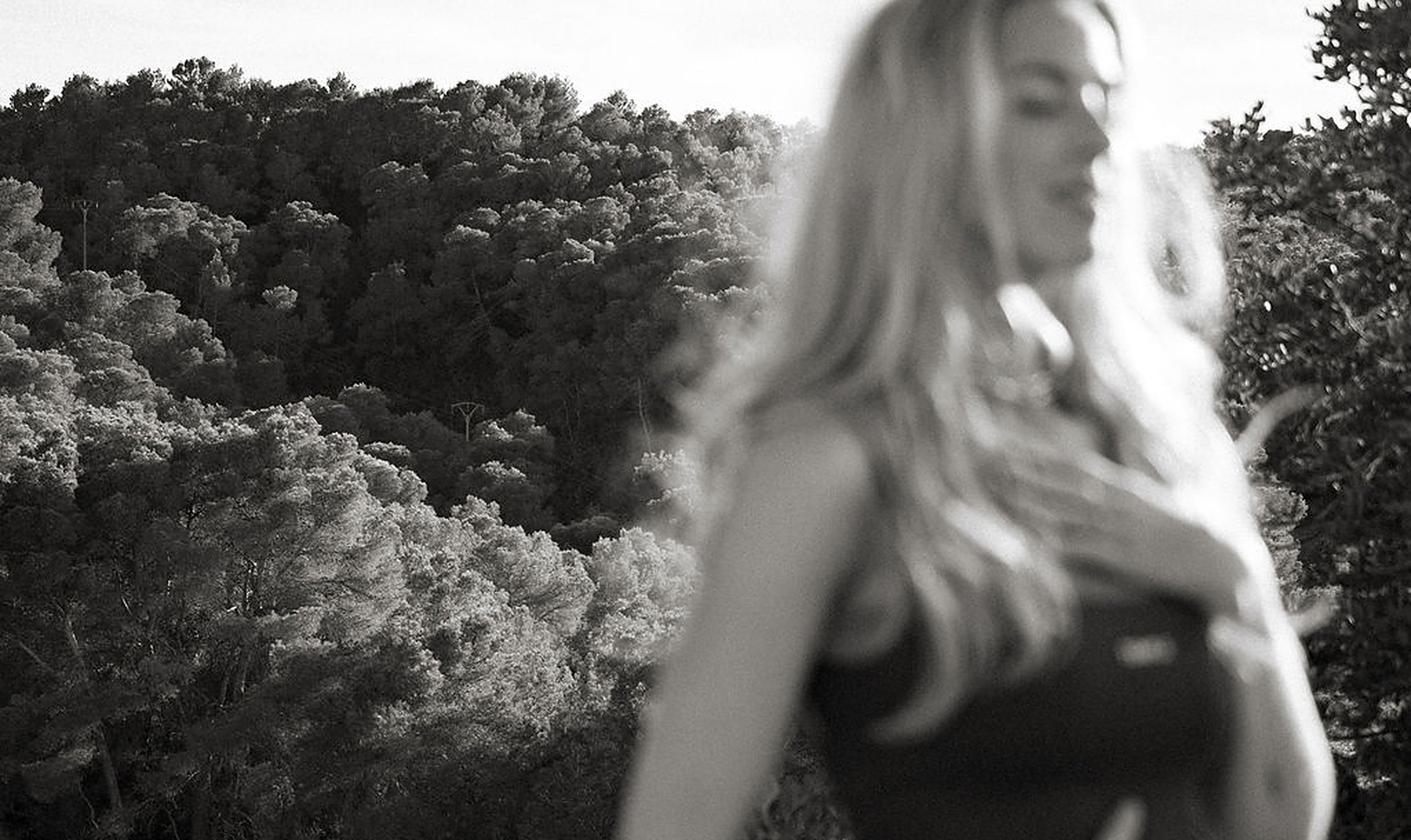 Black-and-white image of a woman outdoors with a hand resting on her stomach, quiet body awareness and connection to self