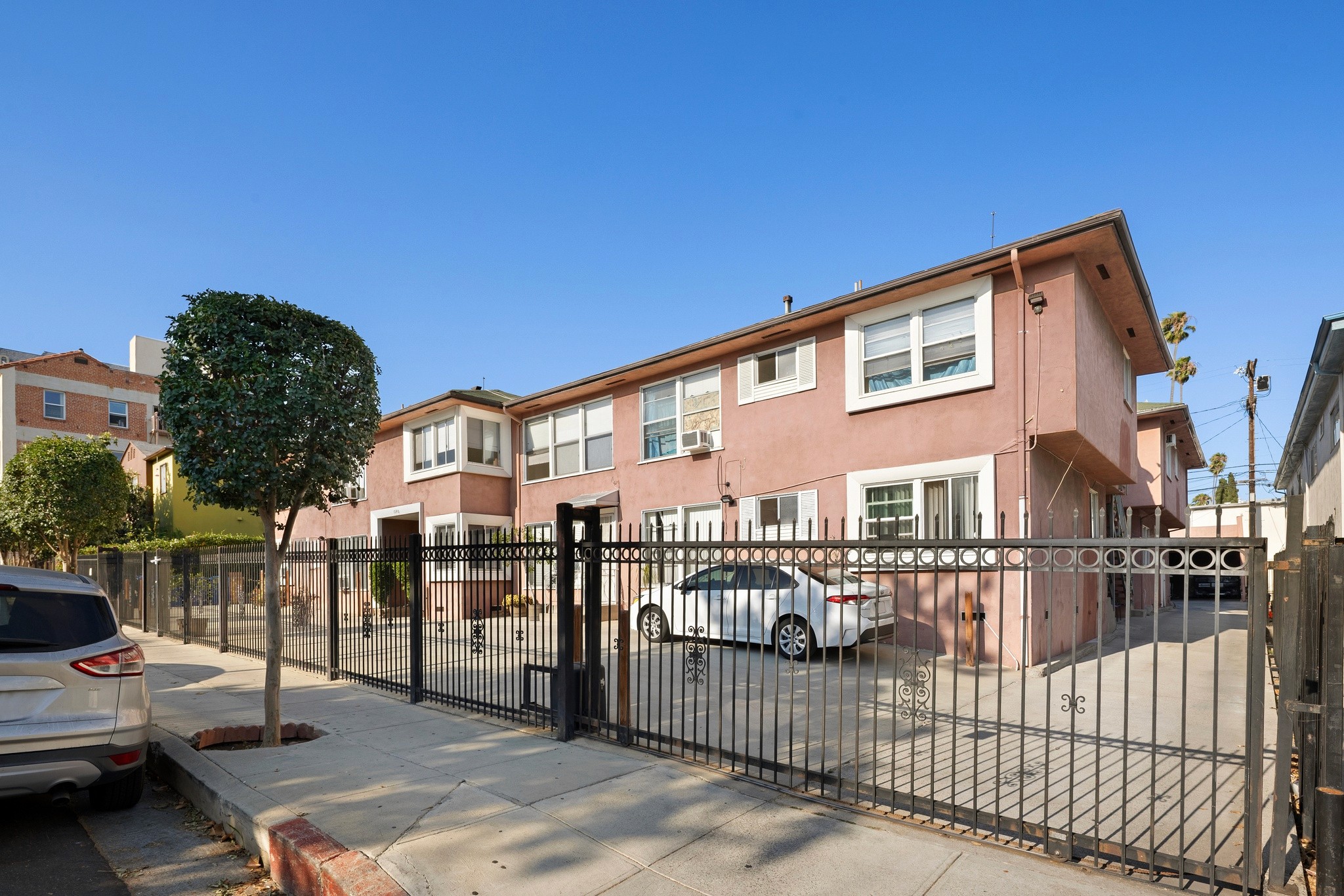 1640 N Harvard apartment building exterior showing peach stucco walls, white windows, and wooden planters on street