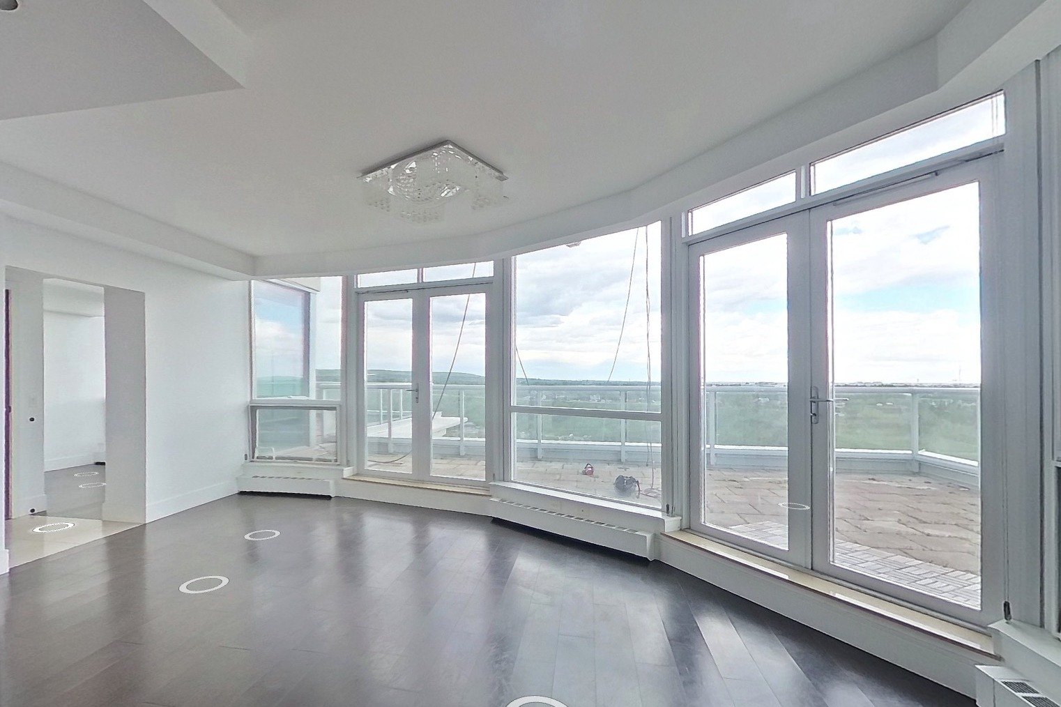 Eau Claire dining room before: empty curved room with dark floors and a crystal fixture