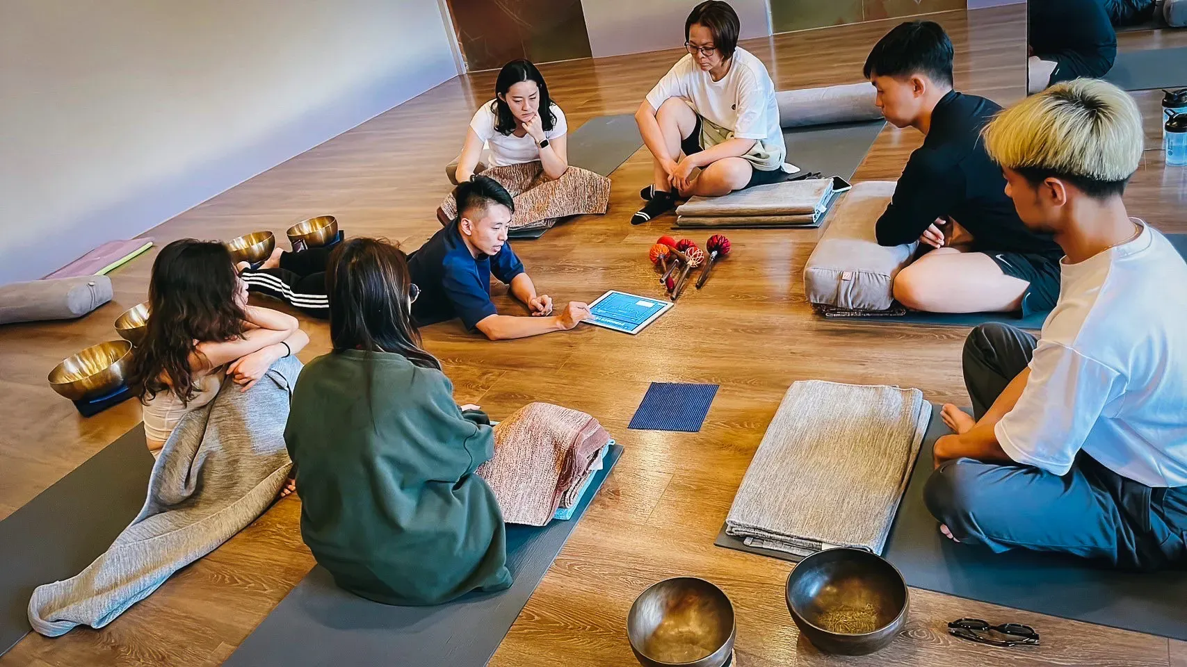 引導師Sunny運用平板輔助教學,向學員說明如何結合頌缽與 Somatic Experience (體感療癒) 來調節身心。在這個安全的互助圈中,我們學習釋放積累的壓力,讓身心能量透過聲音與覺察恢復流動。