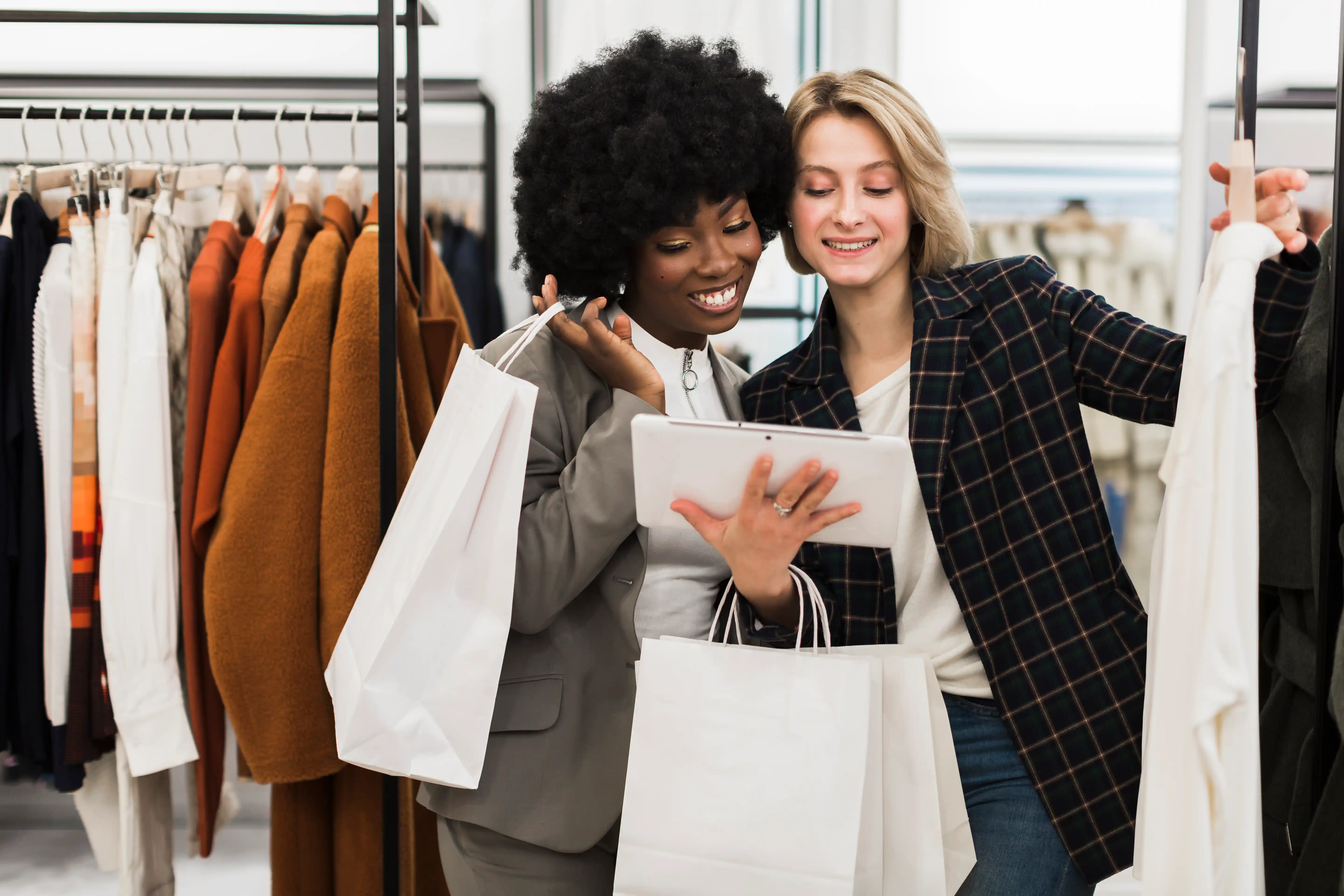 two ladies looking at iPad holding shopping bags