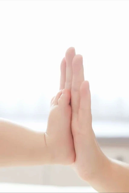 Baby and adult hands touching palm to palm