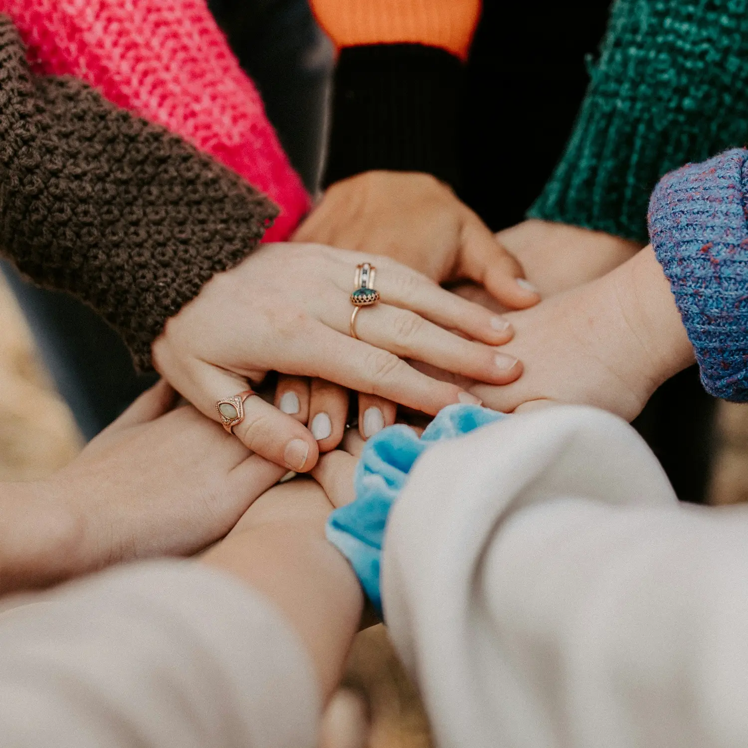 Group of diverse hands stacked together symbolizing unity, support, and inclusivity in gay affirmative therapy
