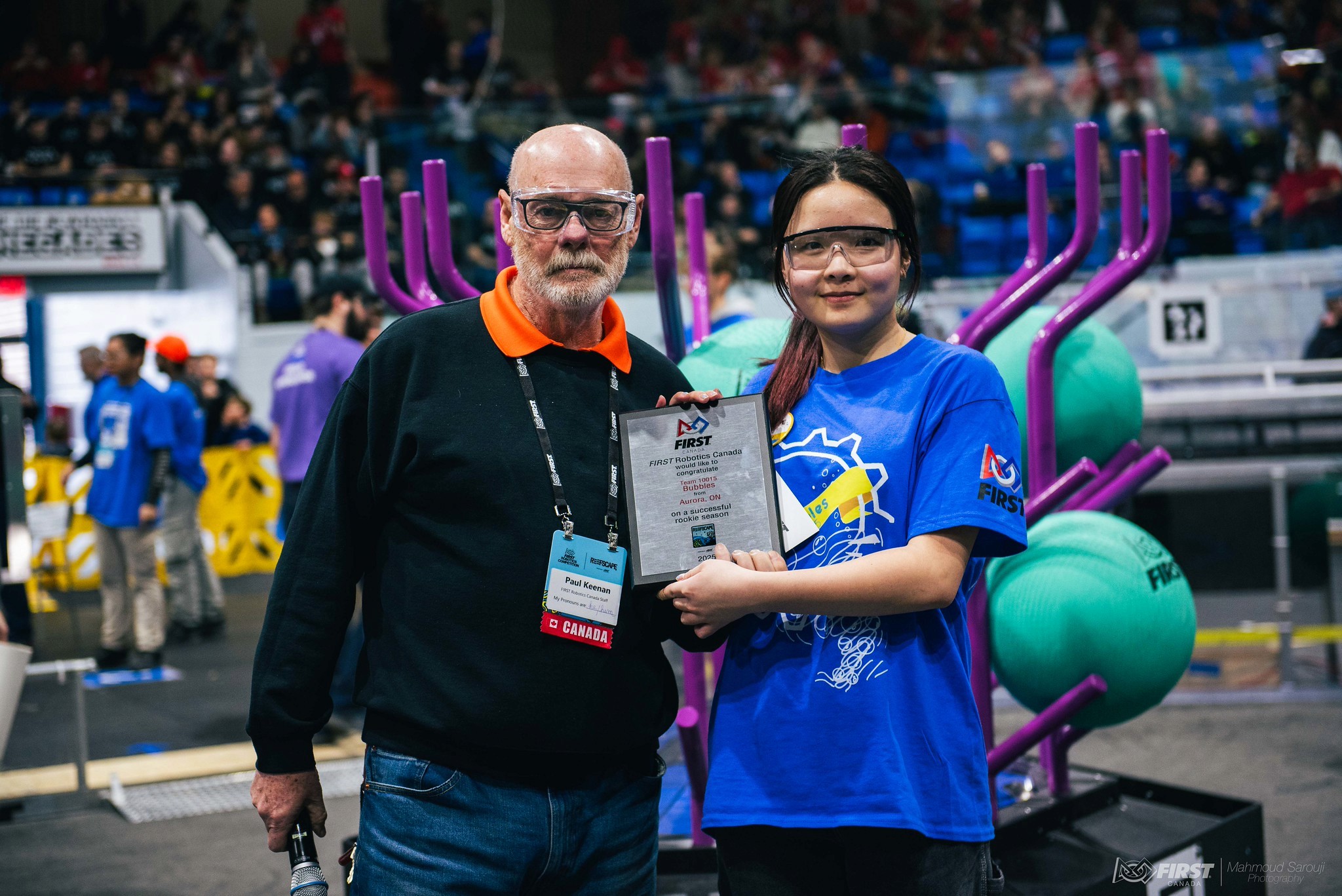 FRC Team 10015 Bubbles co-captain Queena Lin receives a rookie season recognition plaque from Paul Keenan of FIRST Robotics Canada at the 2025 Newmarket District Event.