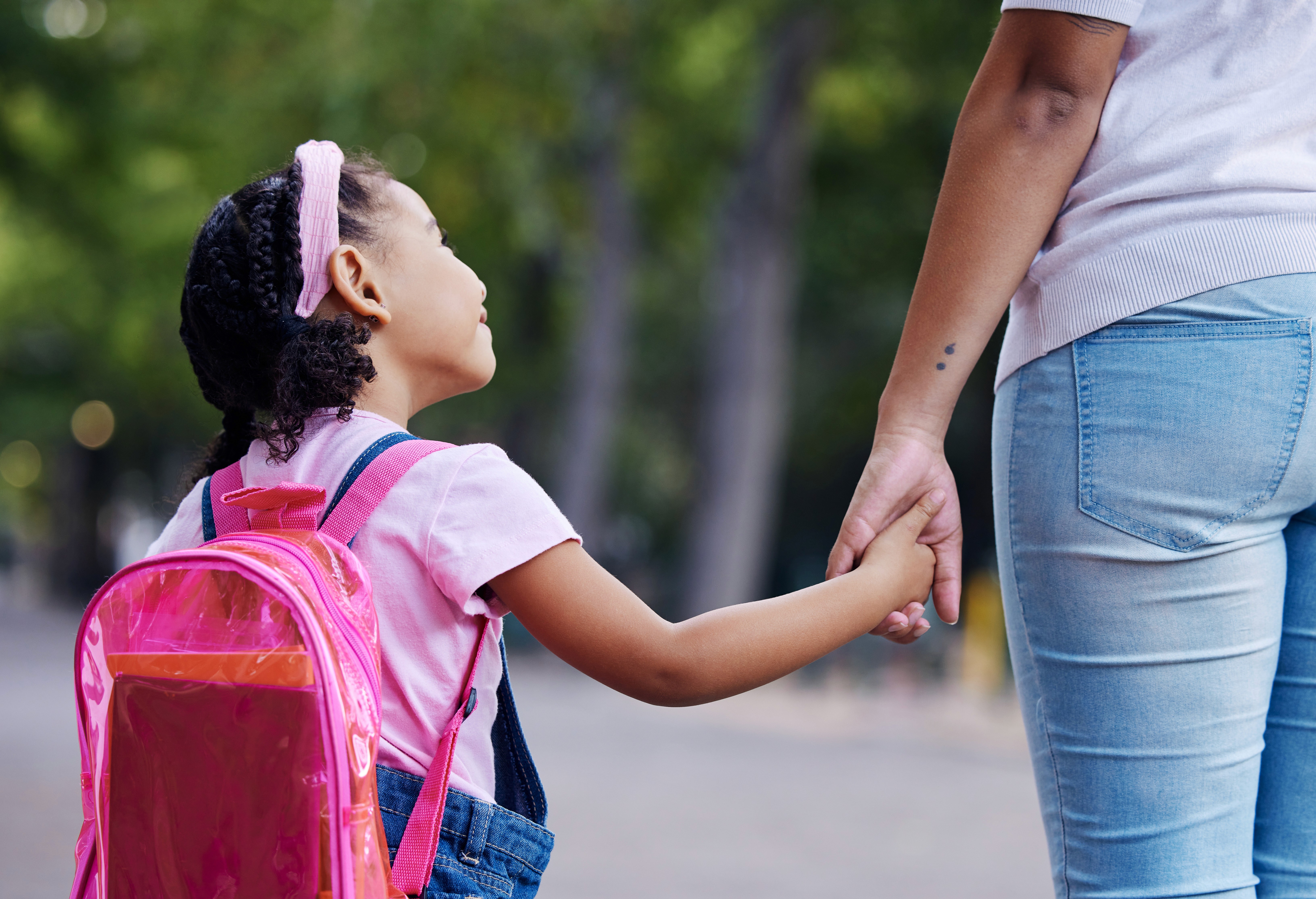 Young child with a backpack holding an adult's hand while looking away, representing parental fitness determinations and child custody proceedings in Essex County Massachusetts family court