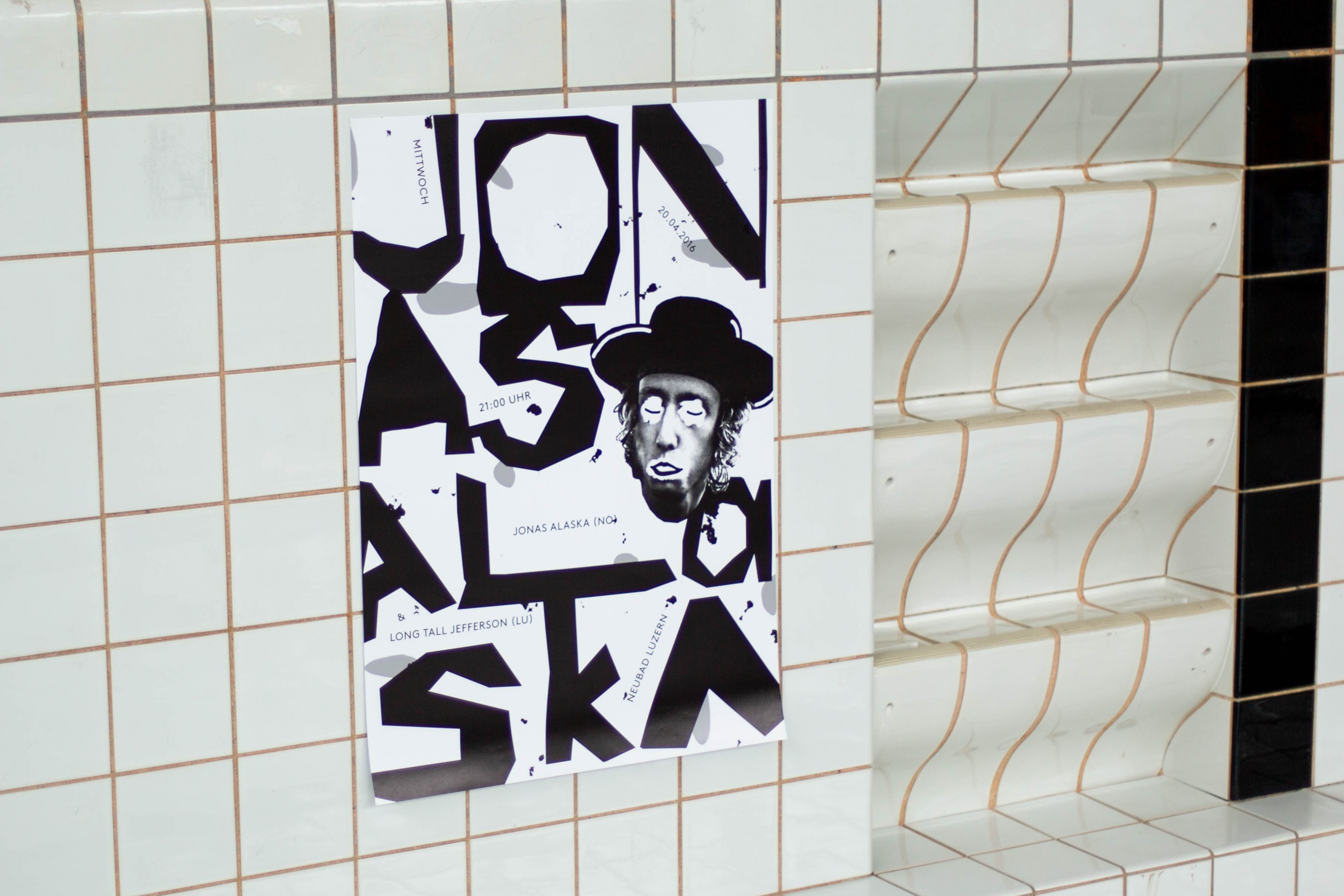 Poster designed for a Jonas Alaska concert with playful typography hanging on the tiled wall of the pool.