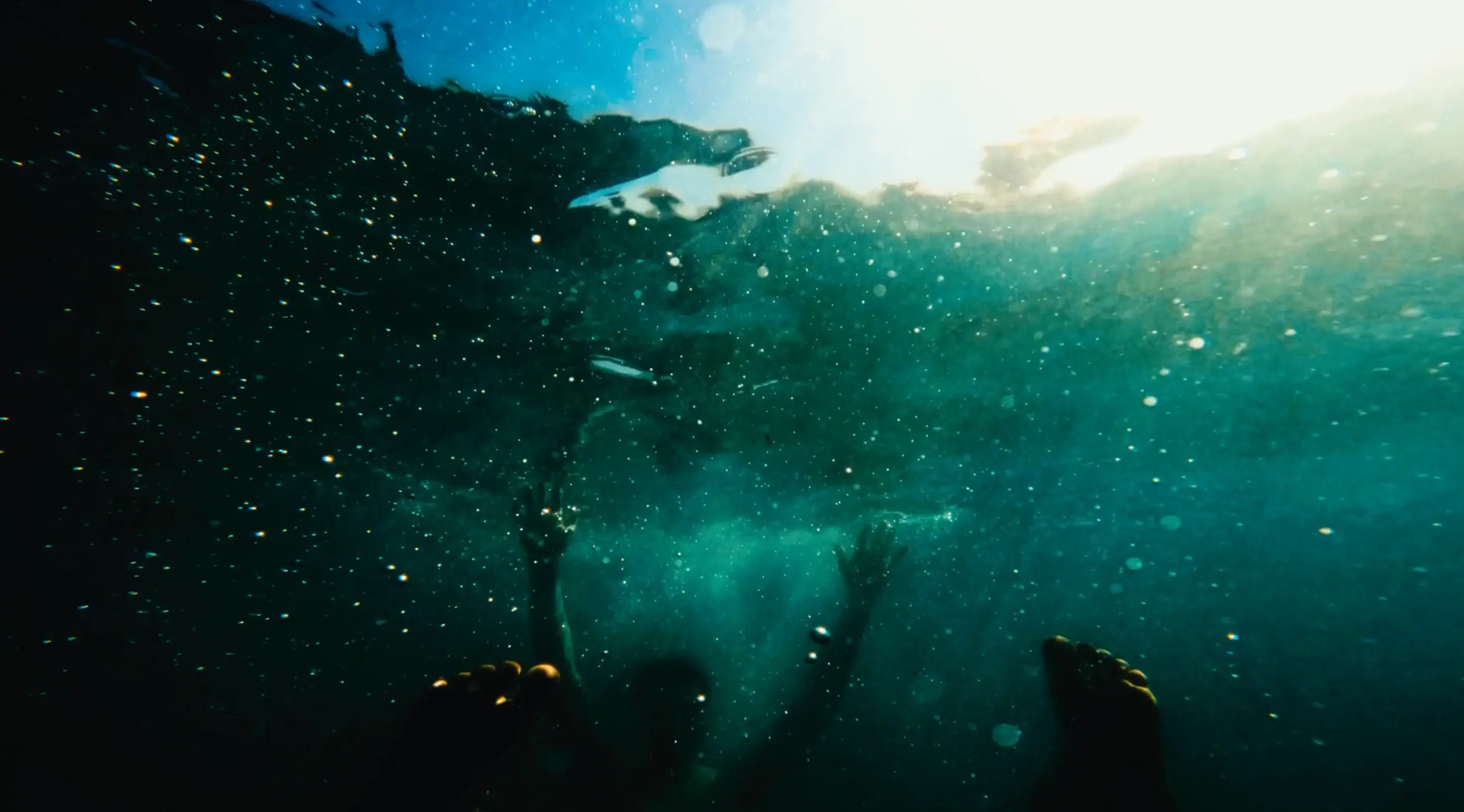 A man underwater looking towards its surface