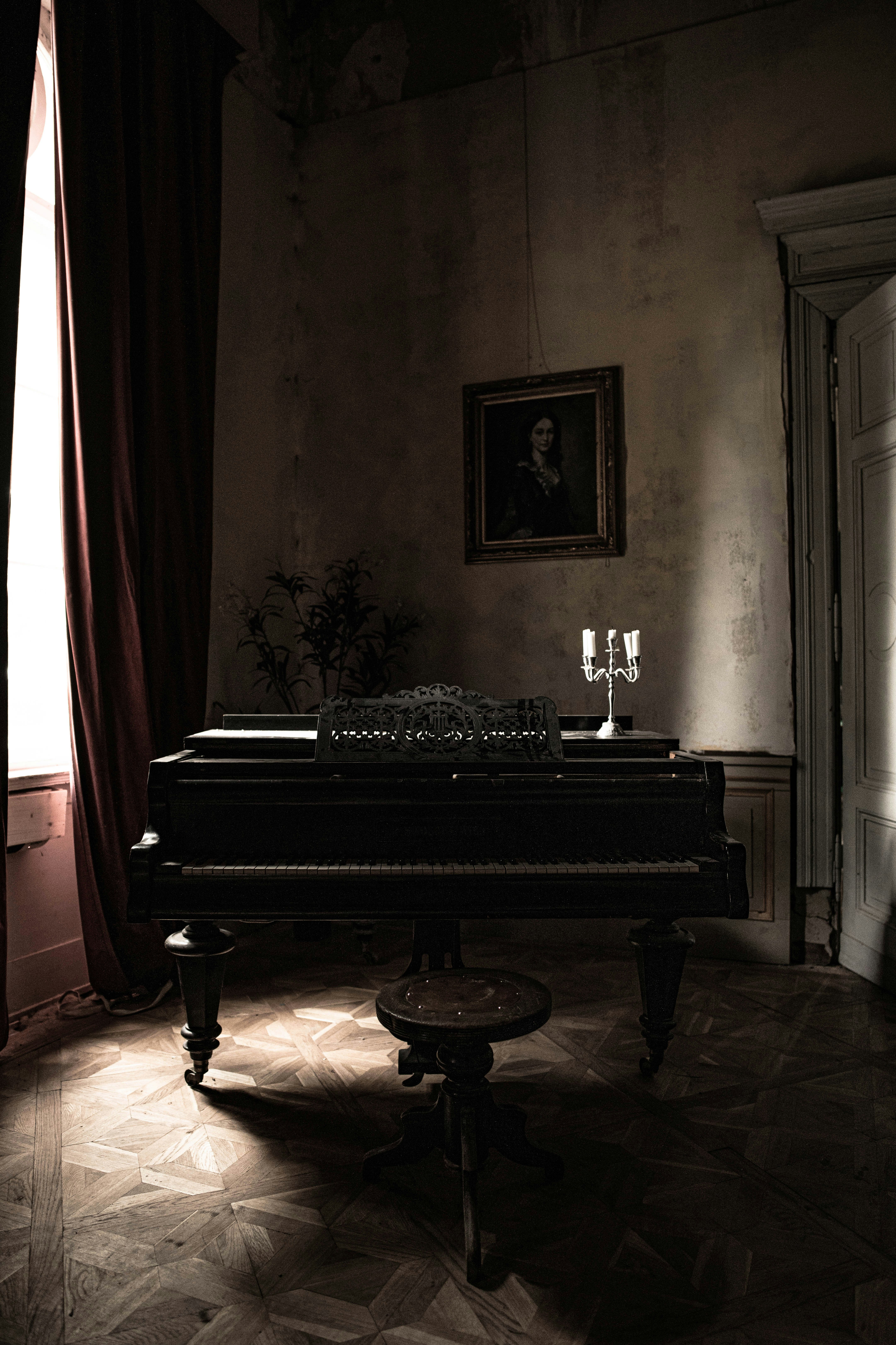 Piano with the candleholder and a chair in a dark room.