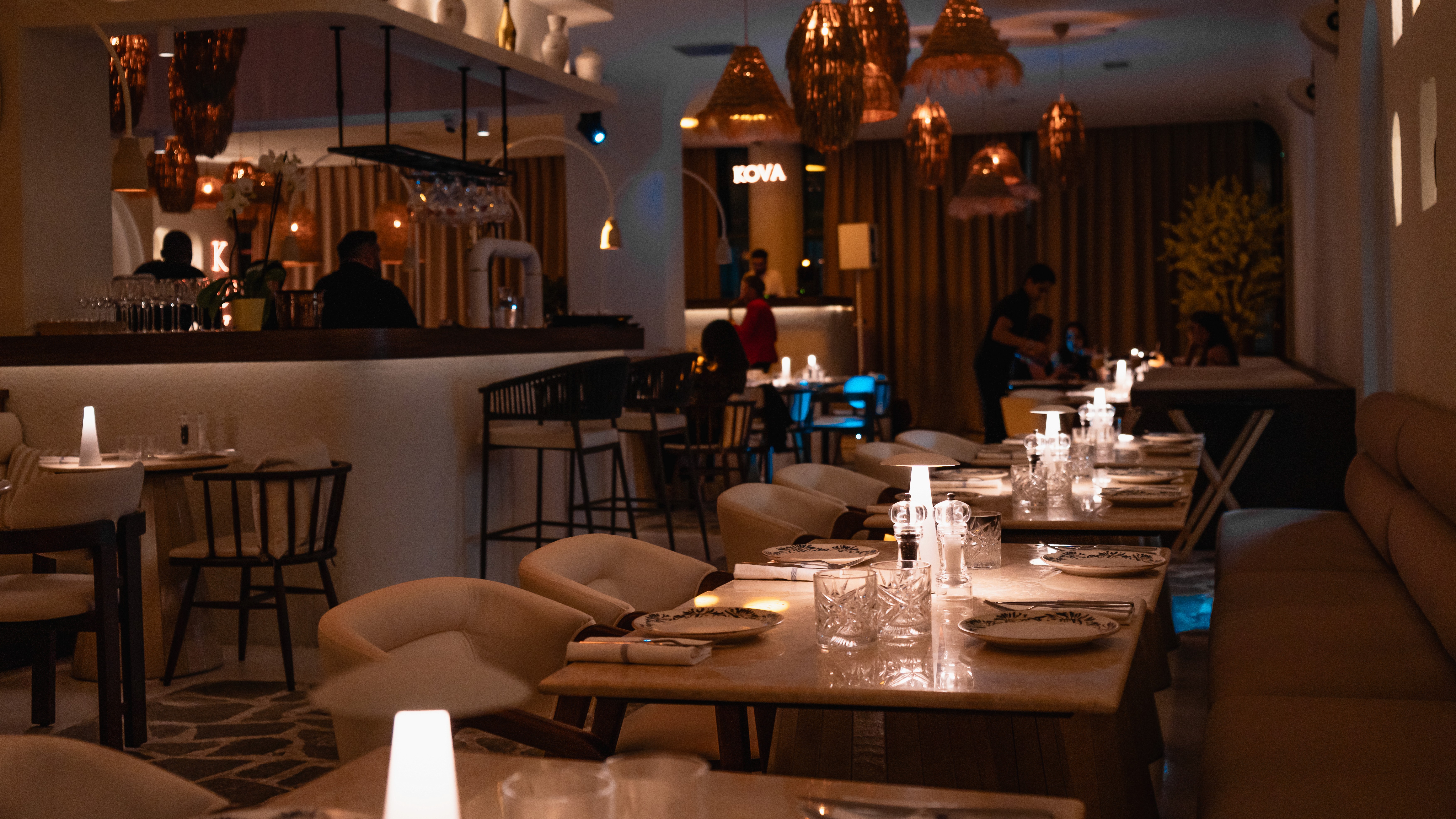 Salle du restaurant Kova à Colombes le soir, tables dressées et ambiance tamisée.