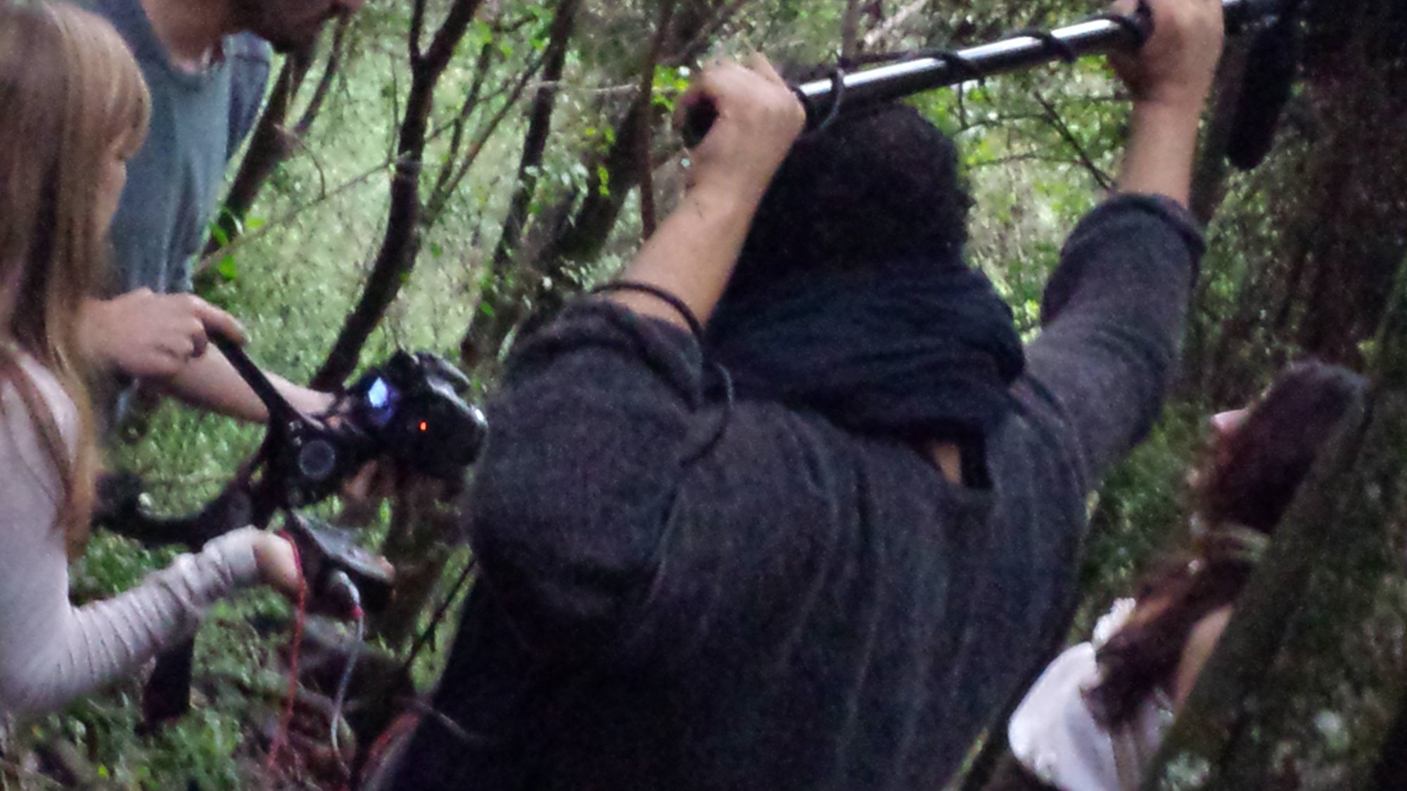 Técnico ergue microfone de vara ao lado de cinegrafista entre árvores, making of com Elisa Aleva