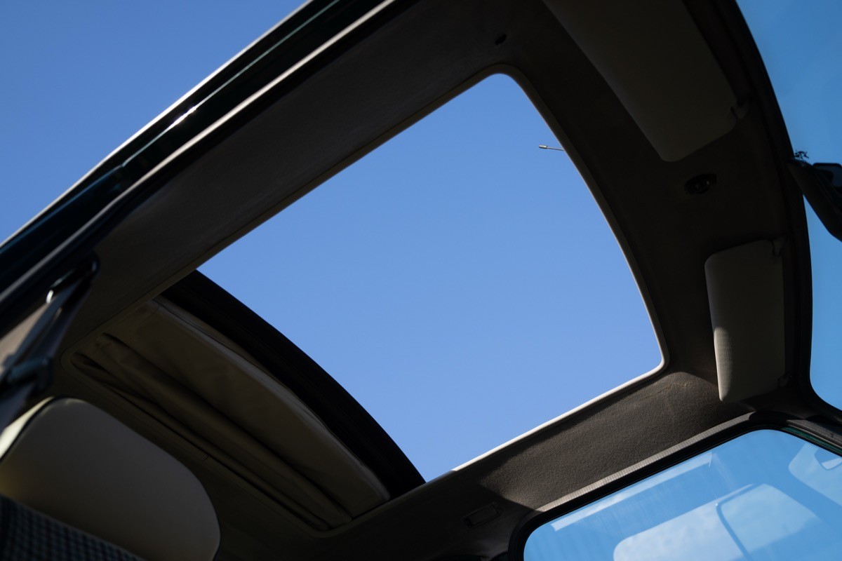 View of a sunroof frame with a clear blue sky visible through the opening.