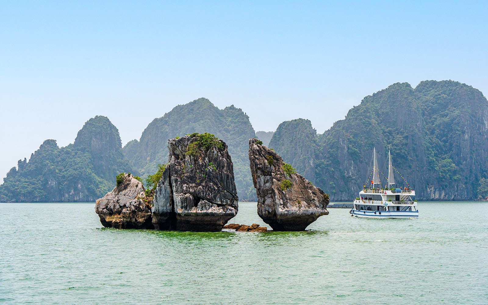 在越南下龙湾附近，有一艘旅游船旁的斗鸡石小岛。