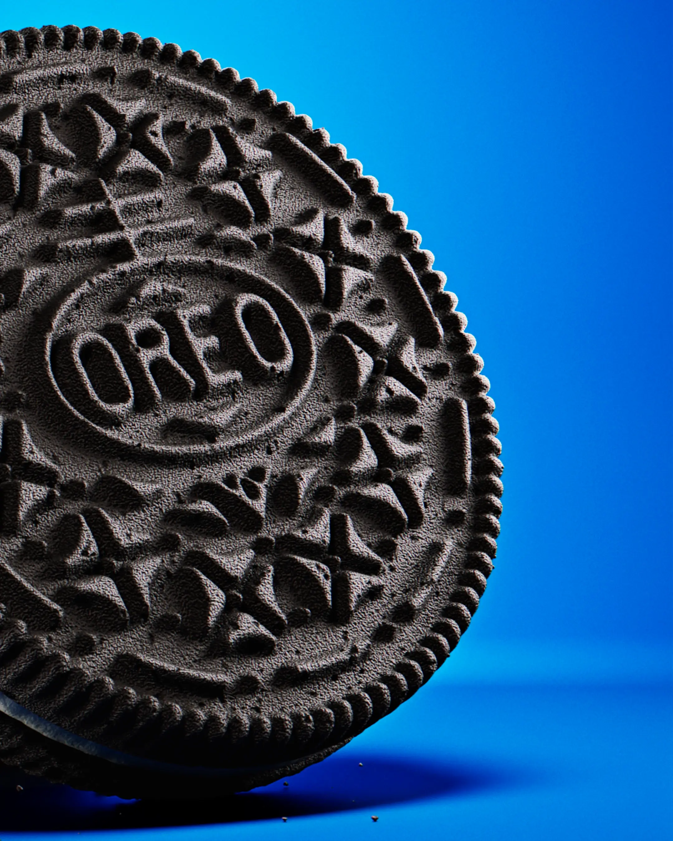 Extreme macro 3D render of an Oreo cookie focusing on the embossed logo and the porous, crunchy texture of the chocolate wafer.