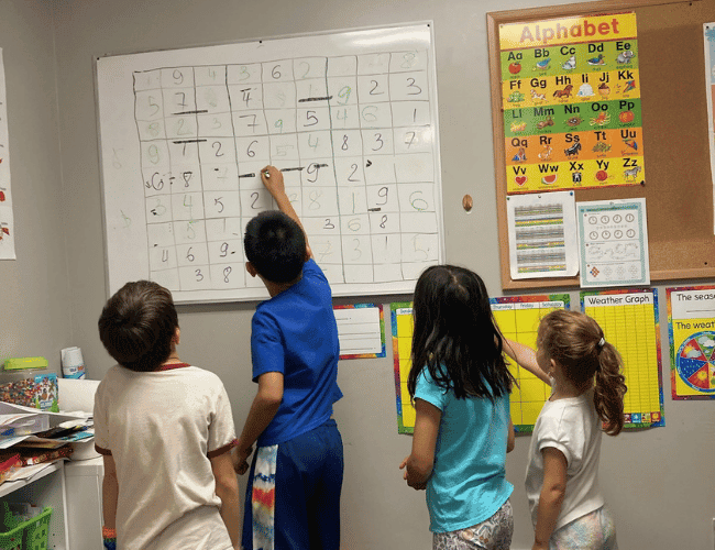 Four kids at a SportPlus math class solving a sudoku math challenge on a whiteboard