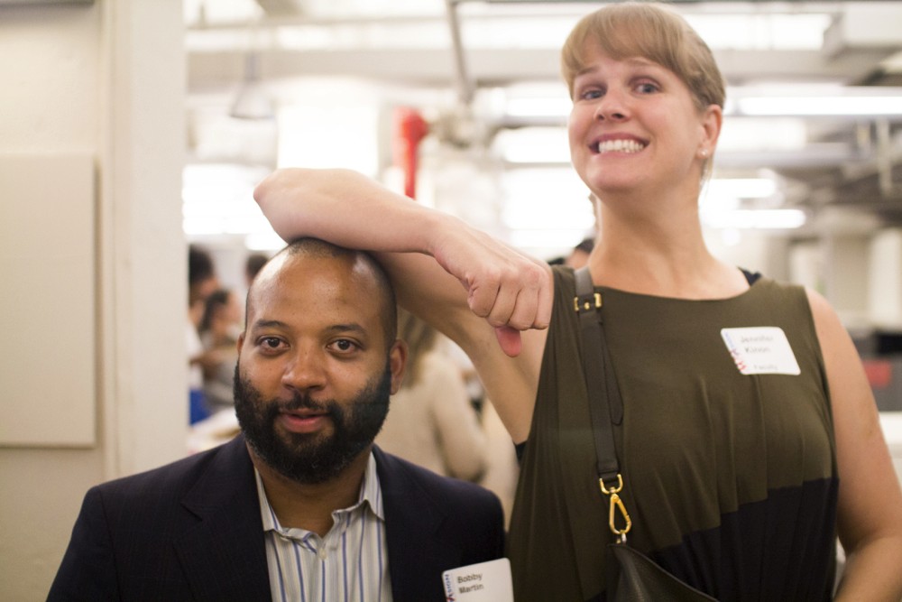 portrait of a taller woman resting her hand on the head of a shorter man