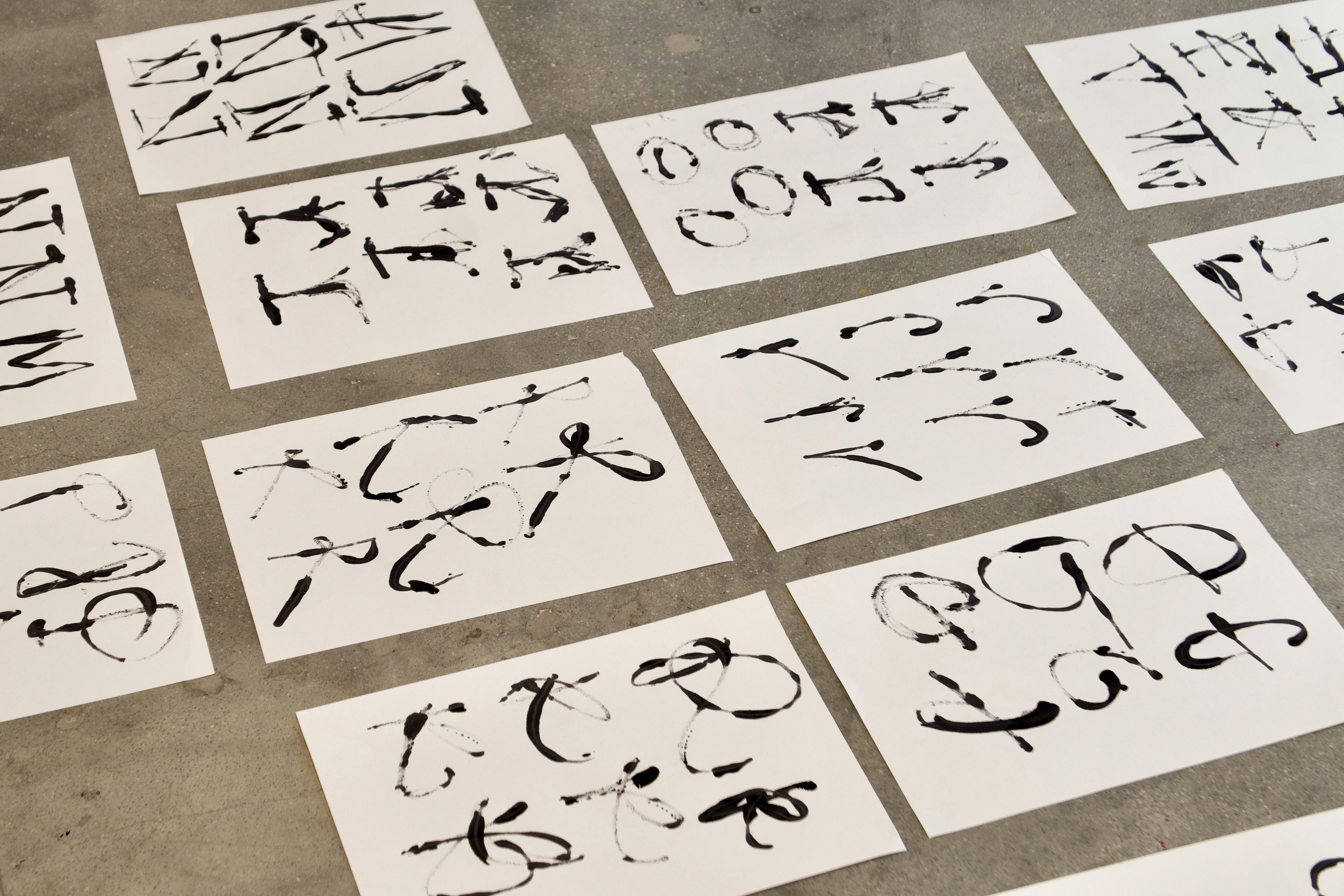 Expressive hand-drawn letters on white paper arranged on the floor