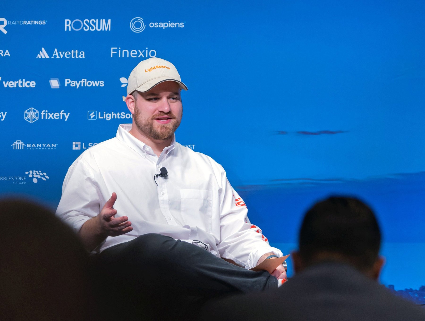 Spencer Penn speaking on a conference panel wearing a LightSource cap