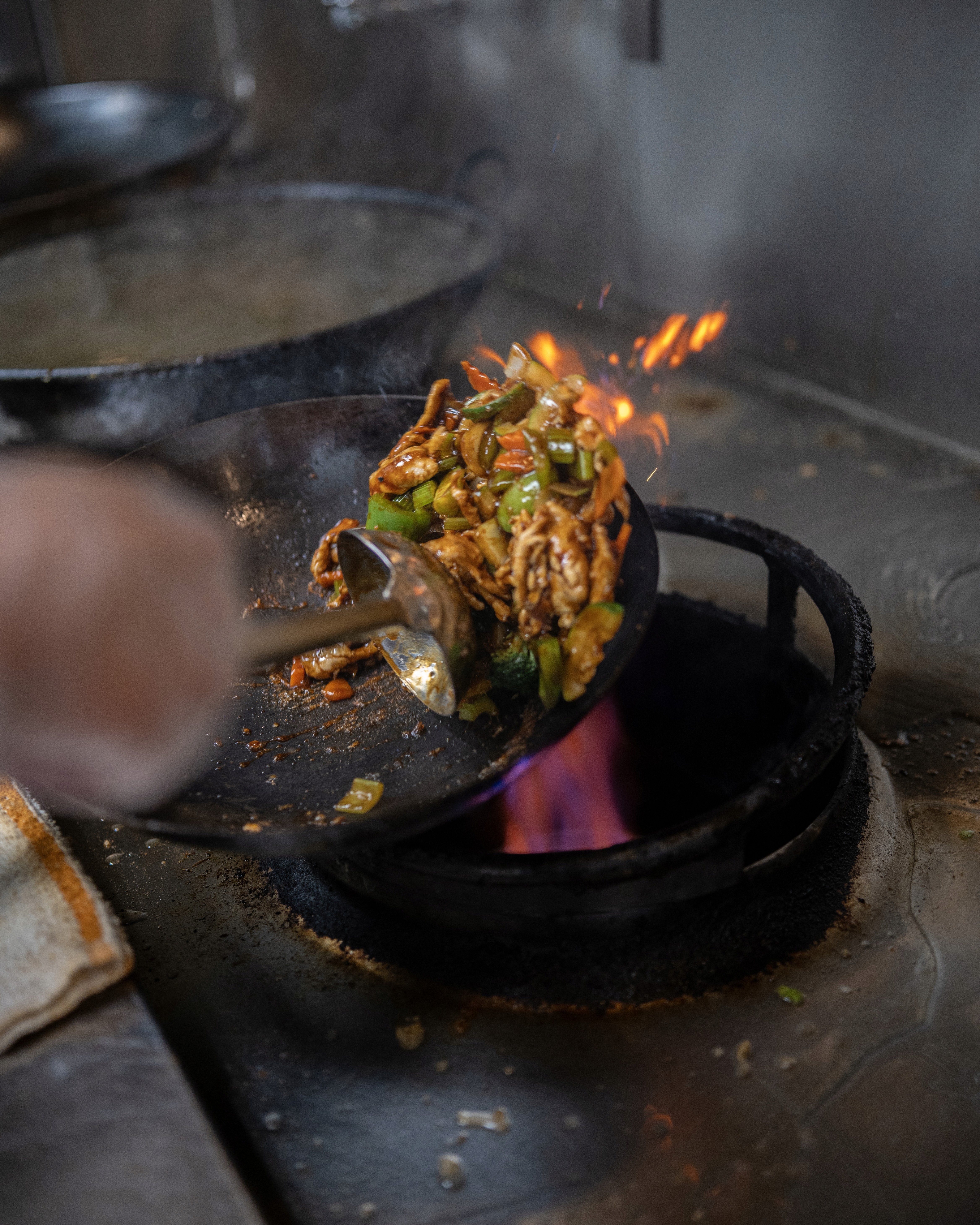 Two plates of pasta topped with herbs, crushed nuts, and a drizzle of sauce, set on a wooden table.