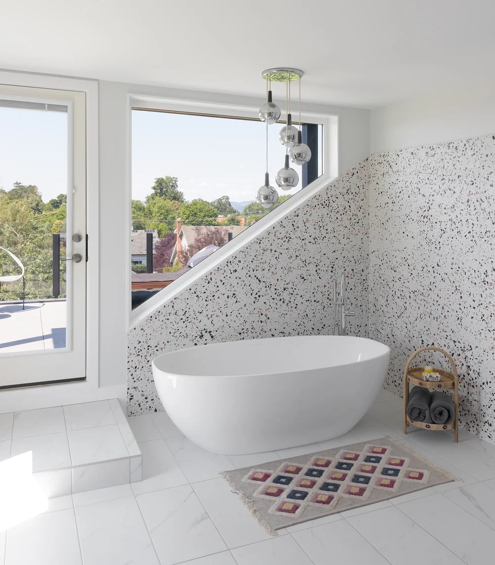 Modern two-story home with large glass windows, warmly lit interiors, and a balcony. Surrounded by trees and a manicured lawn at dusk. Cozy ambiance.