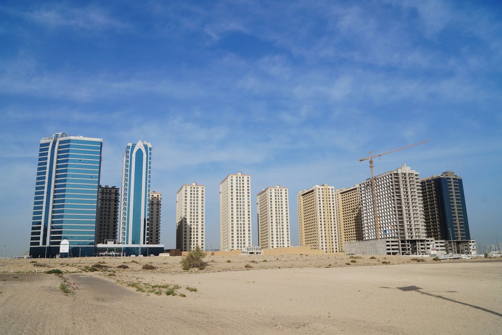 Aerial image of Dubai Production City featuring contemporary architecture and bustling business areas surrounded by greenery