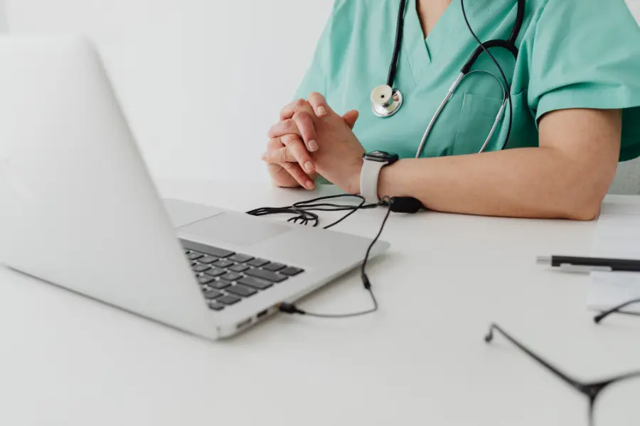 Automated medical billing tasks managed by healthcare worker using laptop with stethoscope on desk.