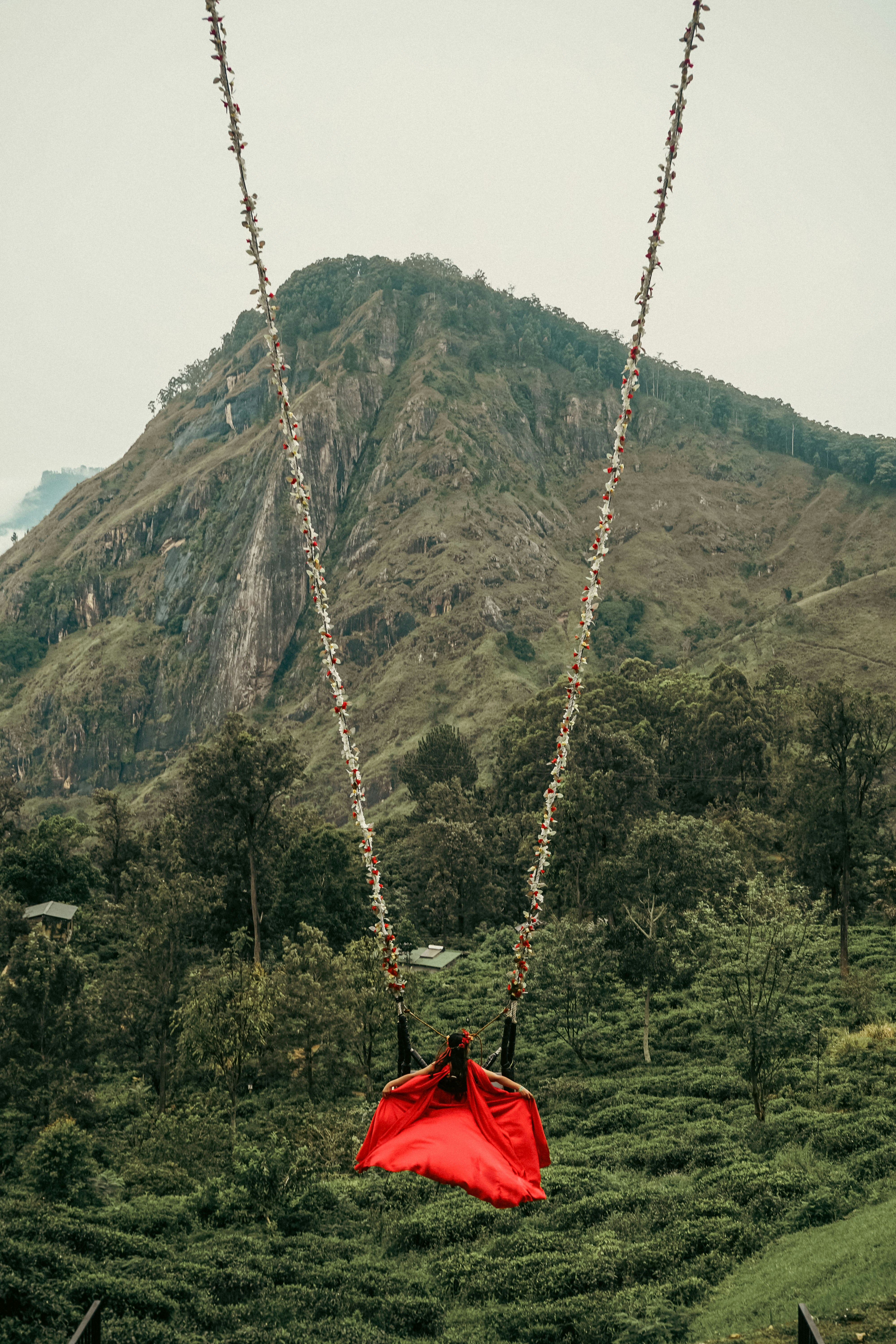 a woman in a red dress is swinging on a rope