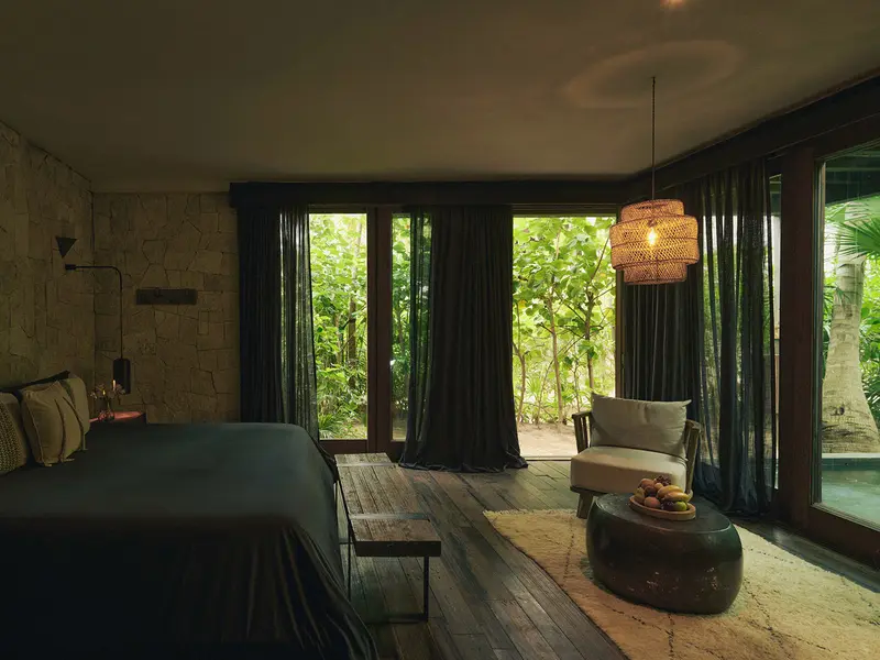 Amplia Arena Suite en Be Tulum con lámpara colgante, área de estar y vistas exuberantes a la selva.